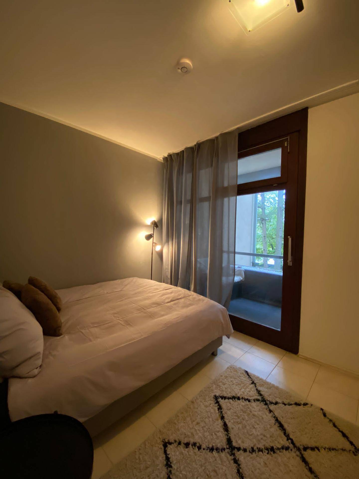 Schlafzimmer mit großem Fenster, das viel Tageslicht hereinlässt und Blick ins Grüne bietet.