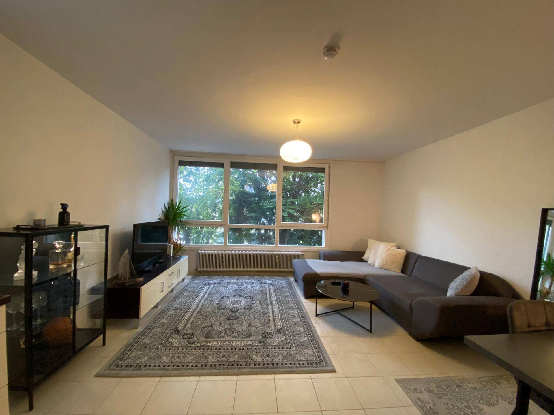 Geräumiges Wohnzimmer mit bequemer L-förmiger Couch und Blick ins Grüne.