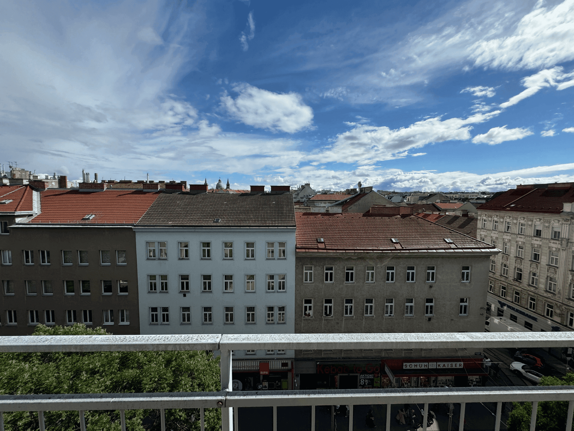 Weitblick über die Dächer einer Stadt mit verschiedenen Gebäuden unter blauem Himmel.