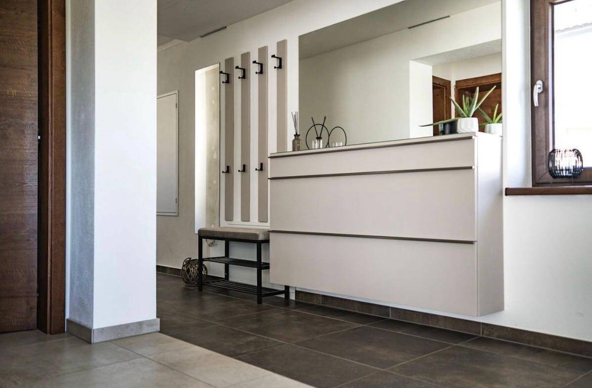 Heller Eingangsbereich mit modernem Schuhschrank, großem Spiegel und Garderobe.