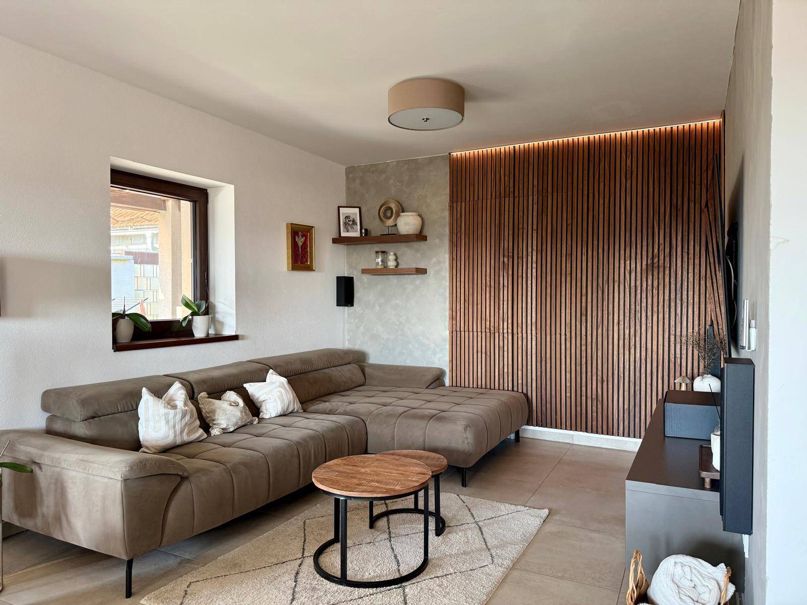 Helles Wohnzimmer mit großem Ecksofa, Holzwand und stilvoller Dekoration.