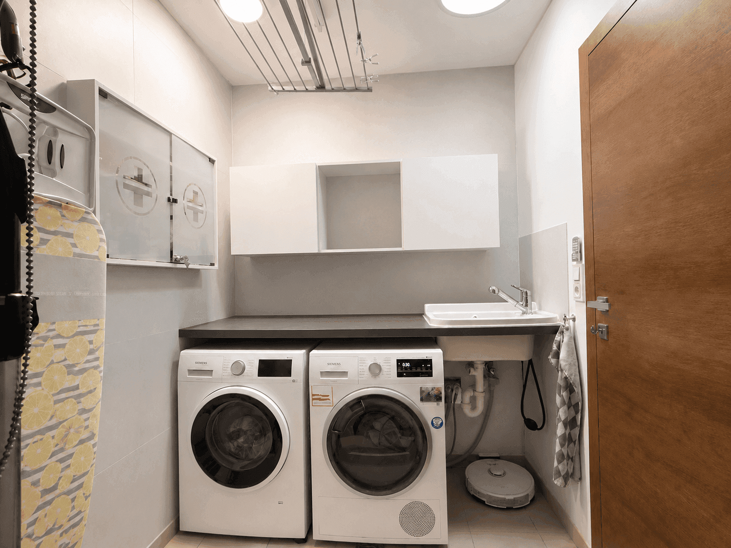 Praktischer Hauswirtschaftsraum mit Waschmaschine, Trockner und Waschbecken.