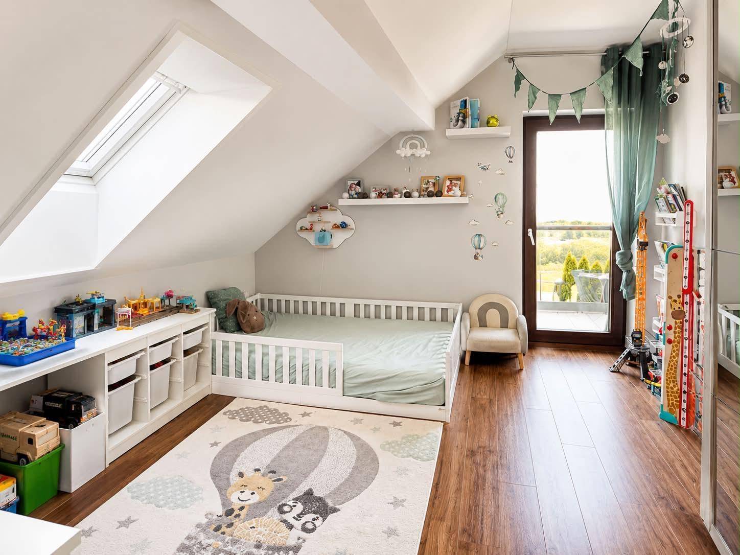 Freundliches Kinderzimmer im Dachgeschoss mit Spielbereich, Dachfenster und Balkonzugang.