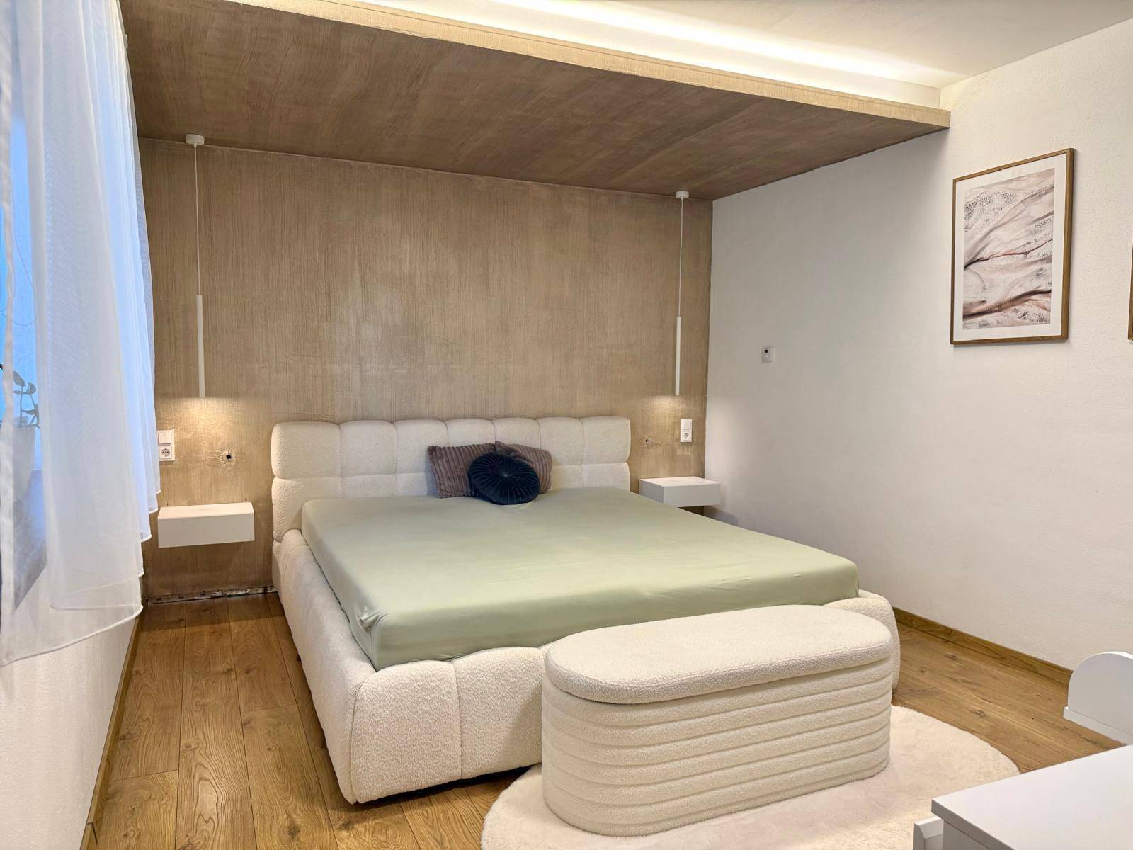 Modernes Schlafzimmer mit großem Doppelbett, indirekter Beleuchtung und Holzboden.