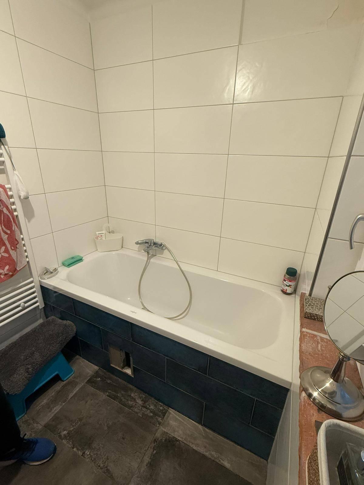 Badezimmer mit einer Badewanne, weißen Fliesen und einem beheizten Handtuchhalter.
