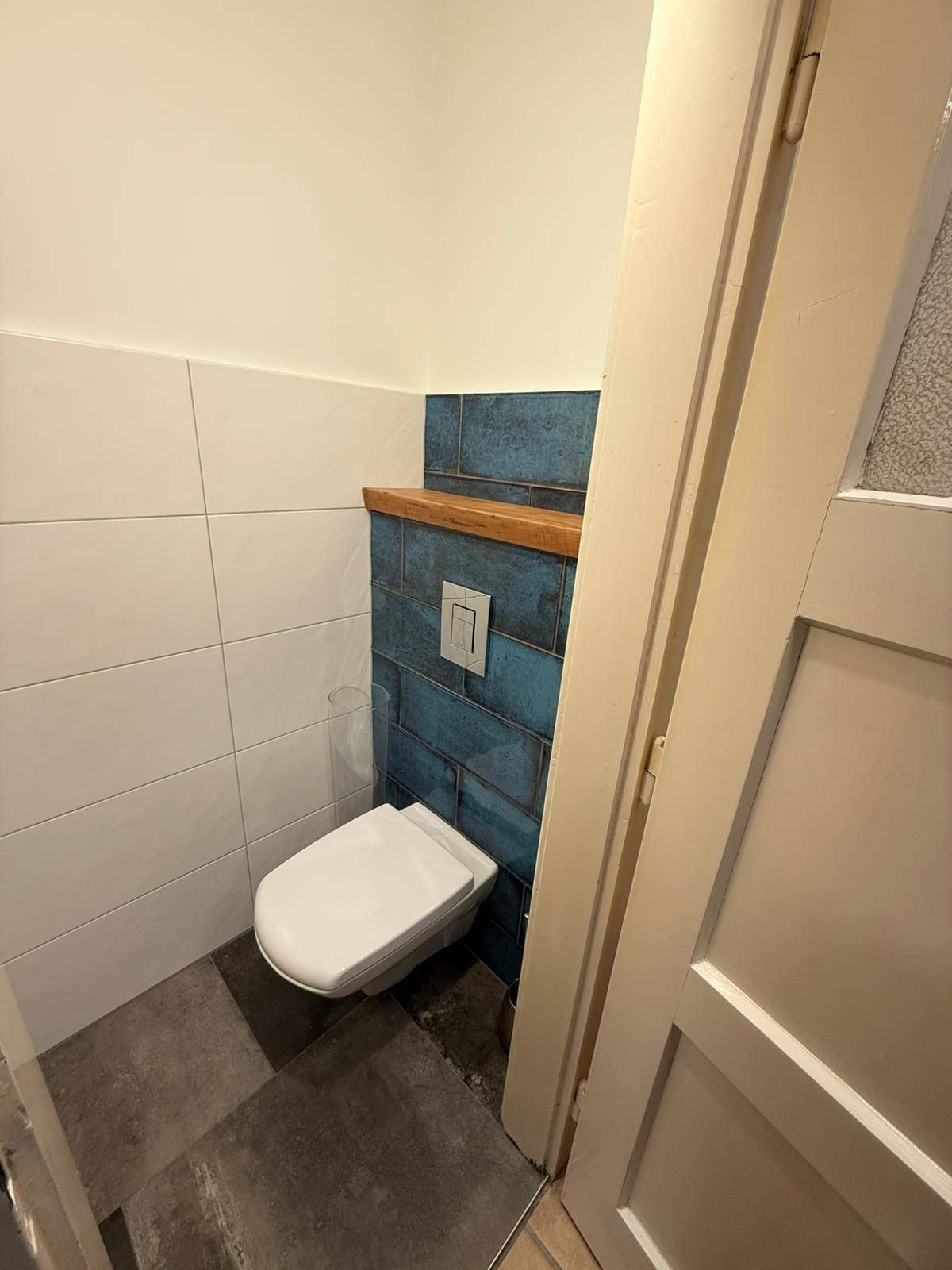 Modernes Gäste-WC mit wandhängender Toilette und blauen sowie weißen Fliesen.