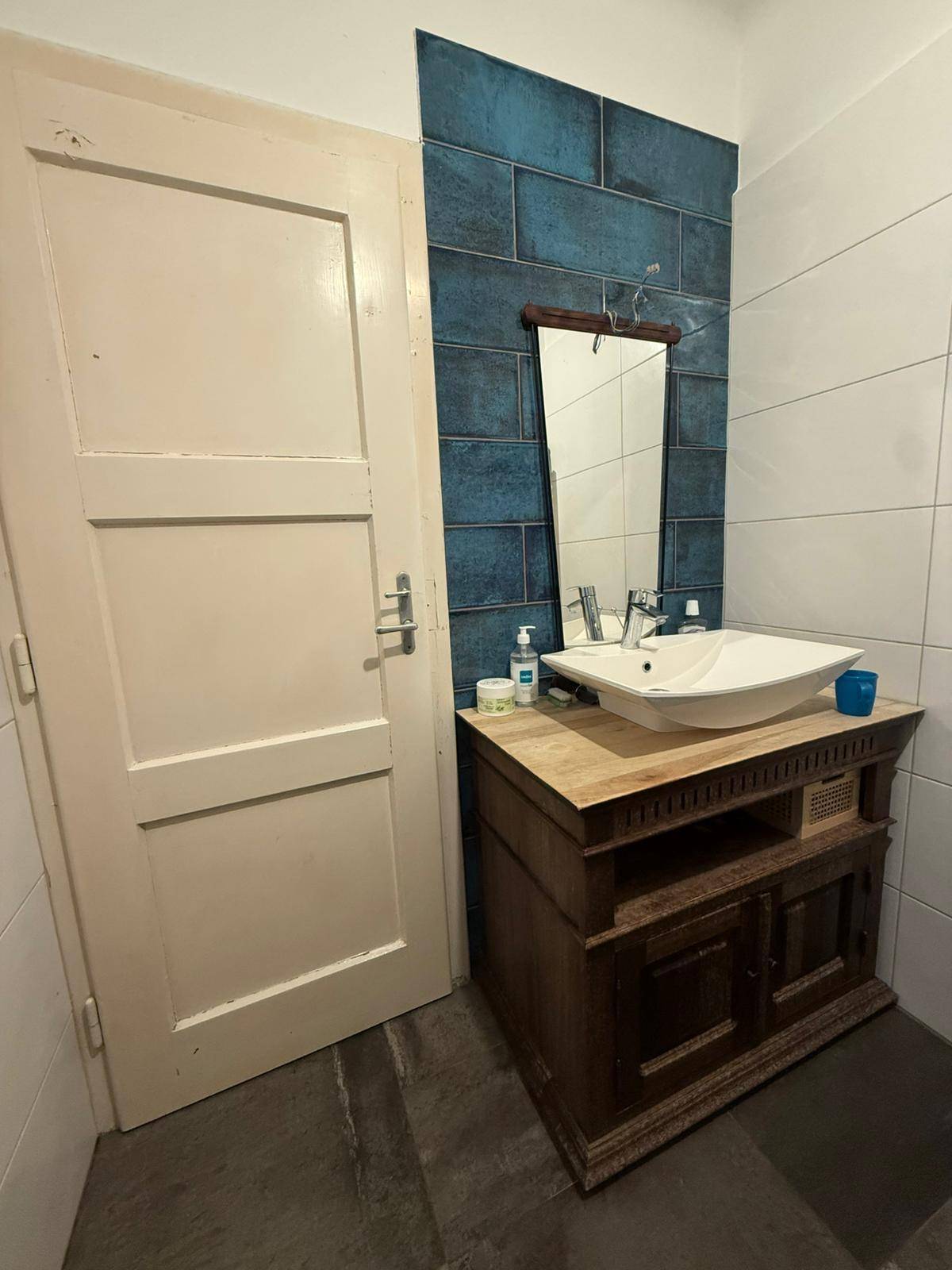 Badezimmer mit einem Waschbecken auf einem Holzunterschrank und einem Spiegel an der Wand.