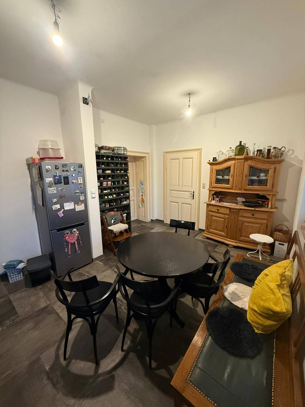 Essbereich in der Küche mit dunklem Tisch, Holzbank und traditionellem Schrank.