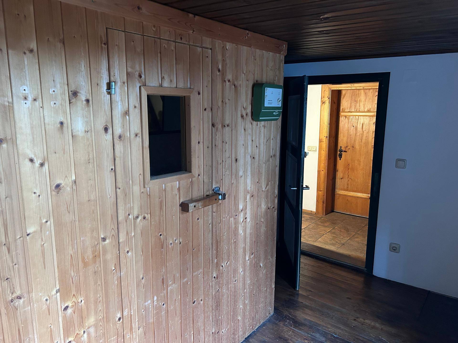 Holzvertäfelte Sauna mit kleiner Fenstertür, bereit für entspannende Momente im Haus.
