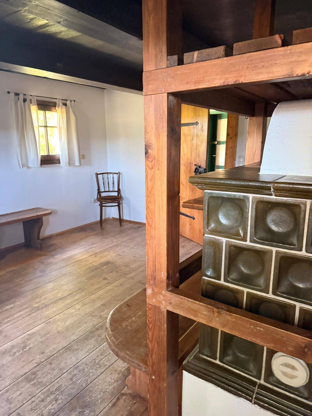 Gemütlicher Essbereich mit traditionellem Kachelofen und Holzboden im Landhausstil.