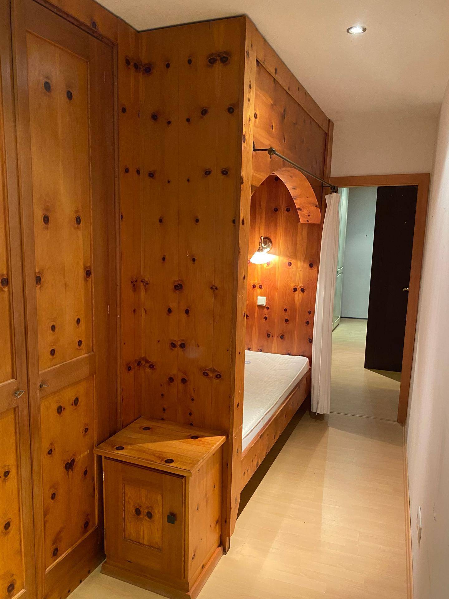 Gemütliches Schlafzimmer mit eingebautem Holzbett und Holzvertäfelung im Landhausstil.