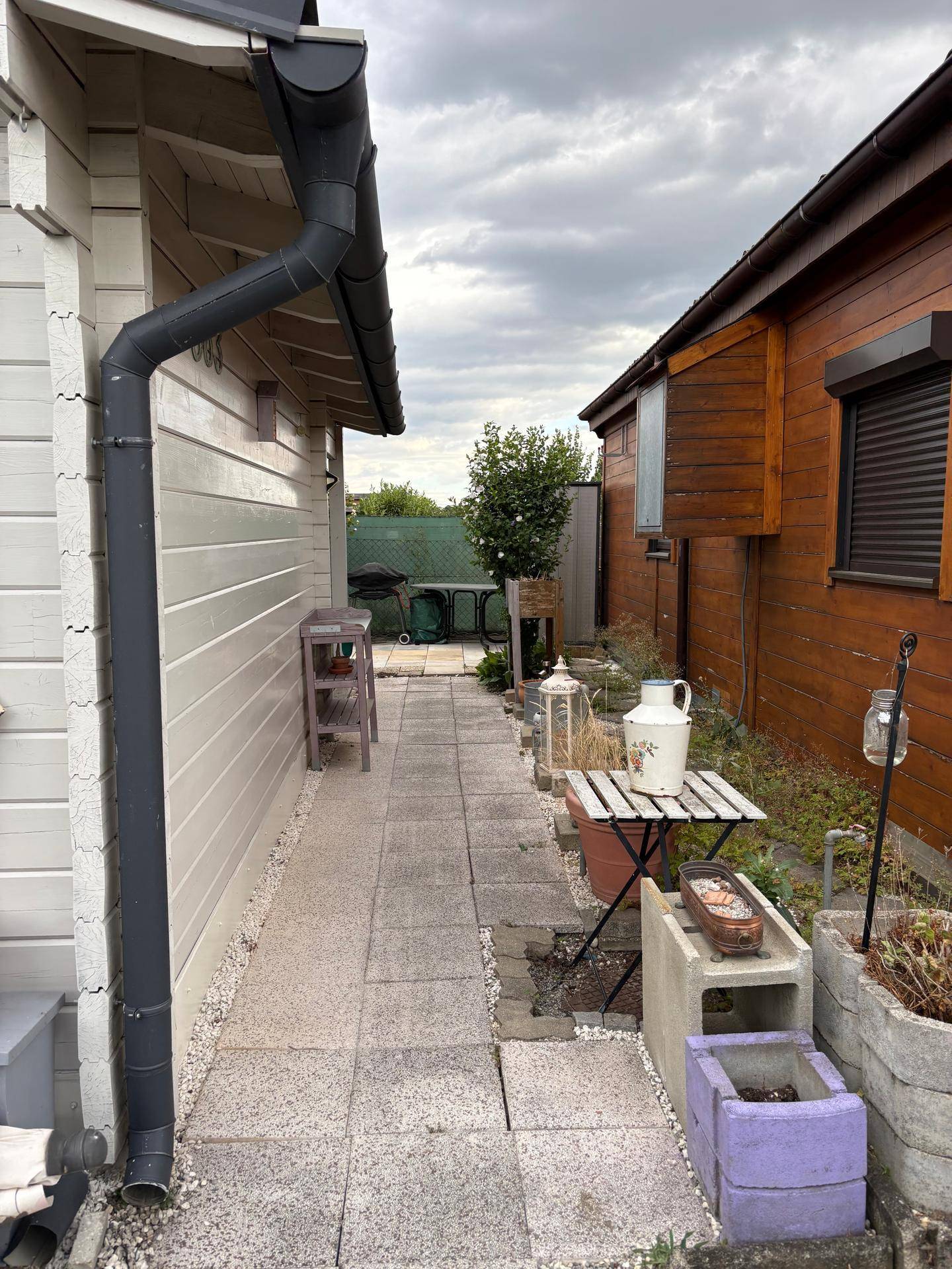 Schmaler gepflasterter Weg zwischen zwei kleinen Häusern mit einfacher Gartendekoration.