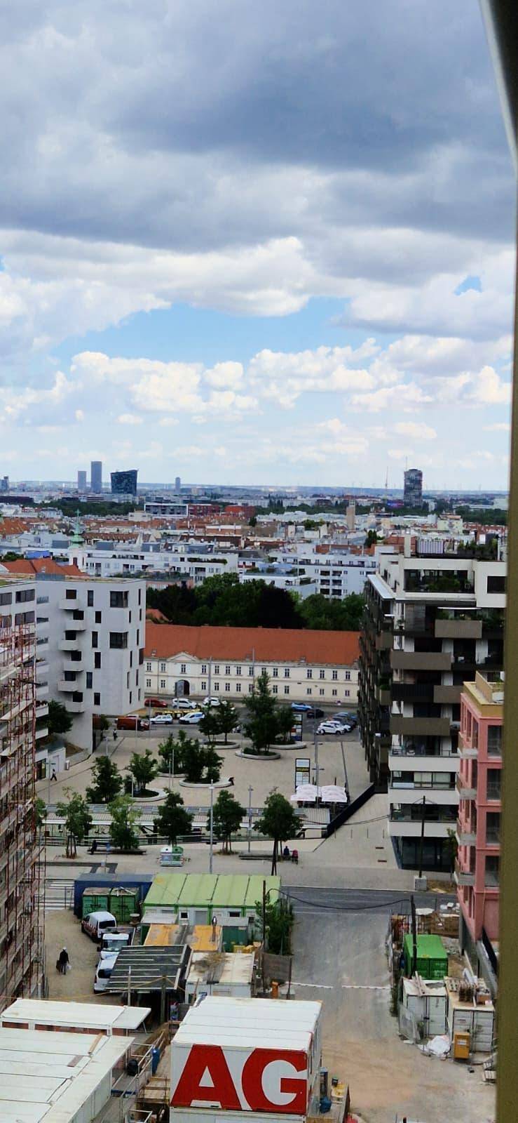 Weitläufiger Stadtblick mit modernen Gebäuden und bewölktem Himmel.
