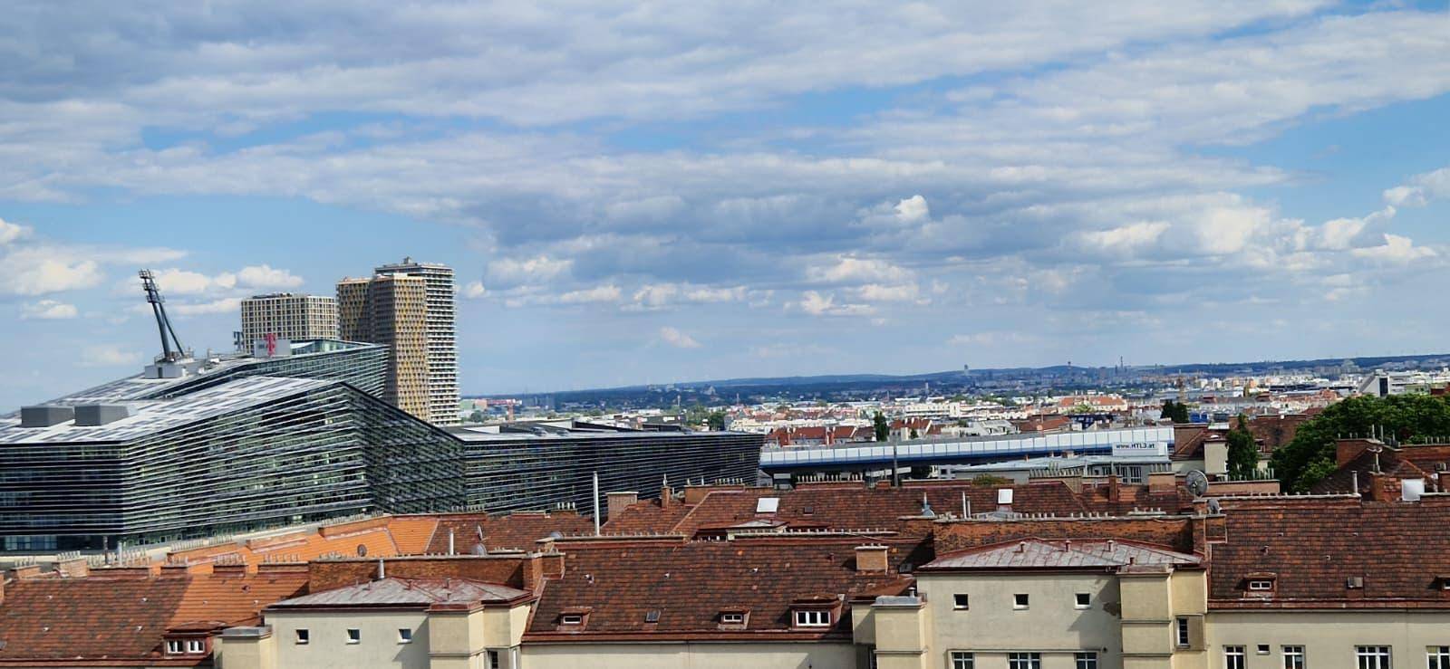 Weitläufiger Stadtblick mit verschiedenen Gebäudetypen unter einem bewölkten Himmel.