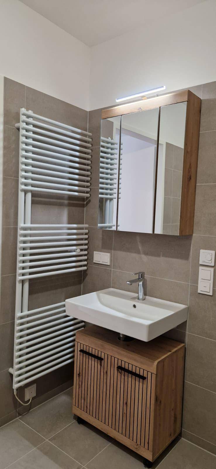Modernes Badezimmer mit Einzelwaschbecken, Spiegelschrank und beheiztem Handtuchhalter.