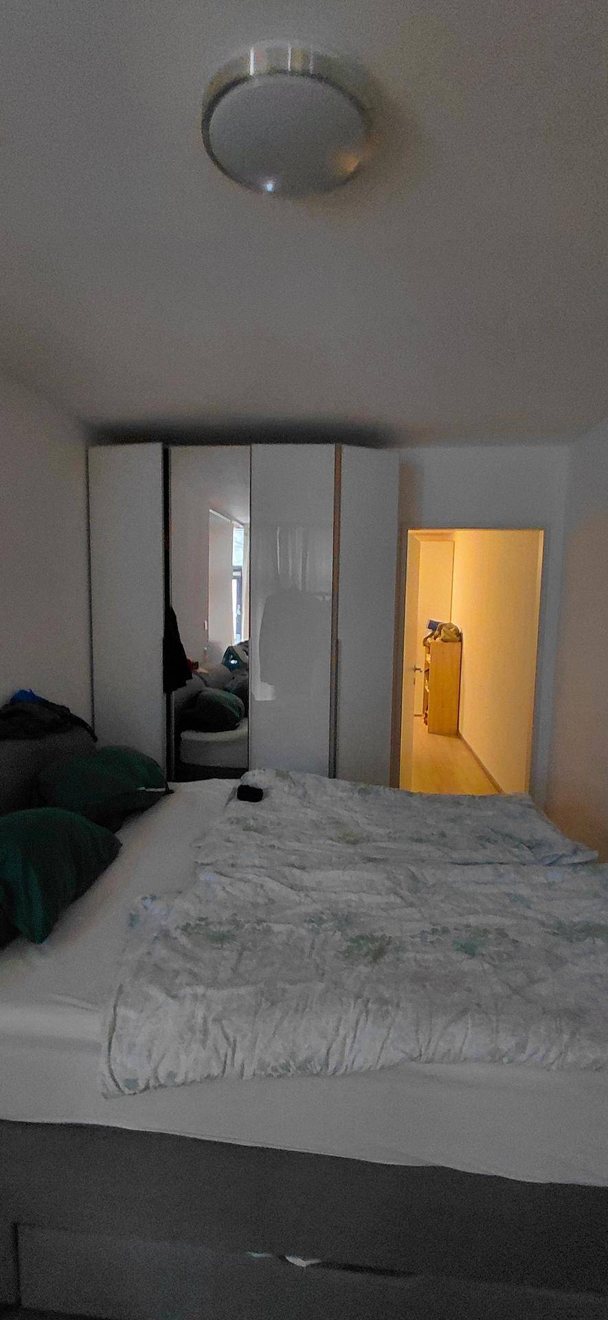 Schlafzimmer mit großem Bett, weißen Kleiderschränken und einem Durchgang zu einem weiteren Raum.