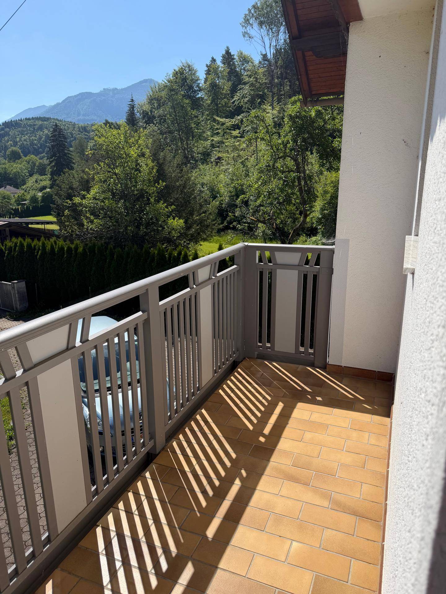 Heller Balkon mit Fliesenboden und Blick auf die umliegende grüne Landschaft.
