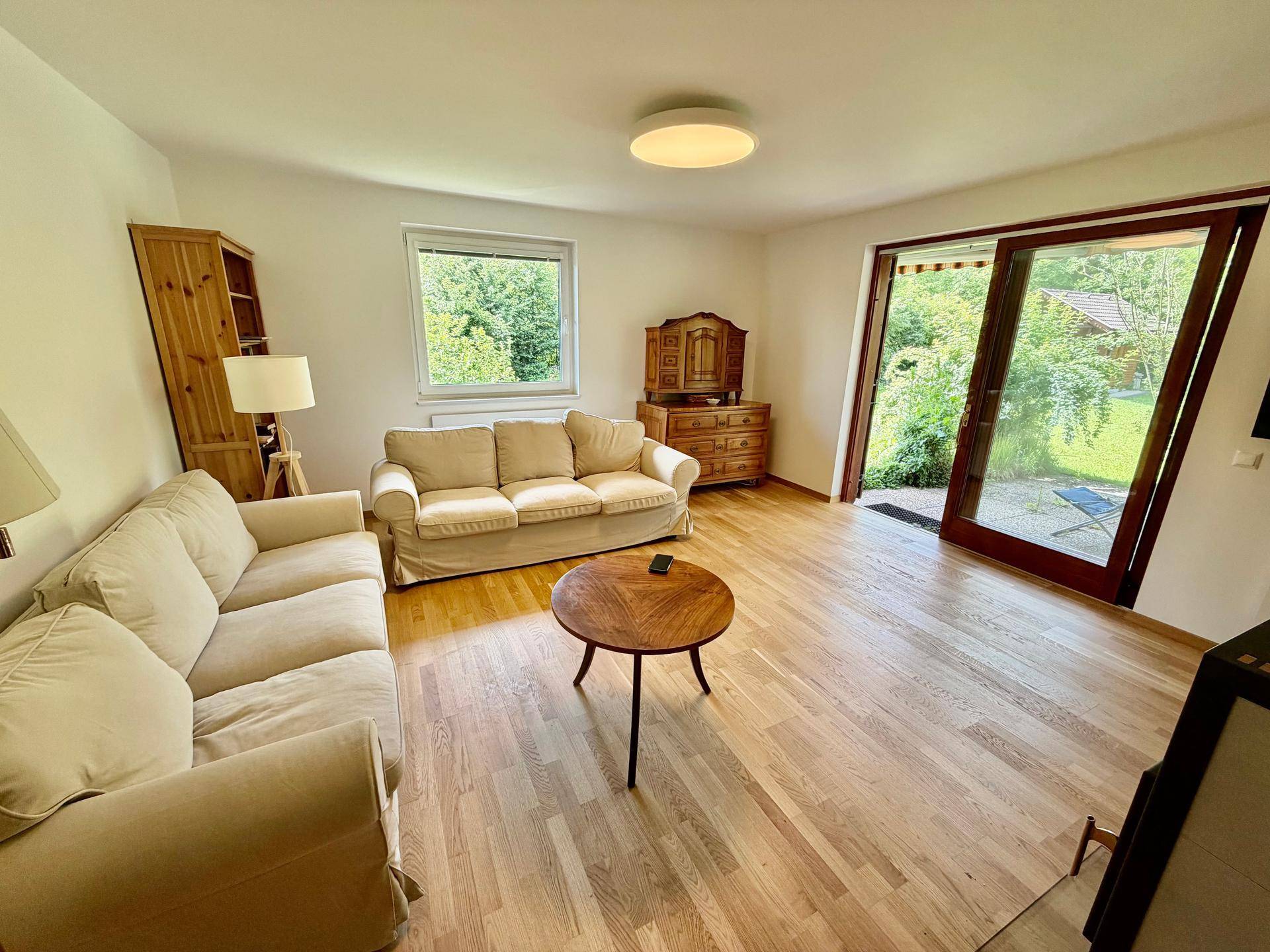 Helles Wohnzimmer mit Parkettboden, zwei Sofas und Zugang zum Garten.