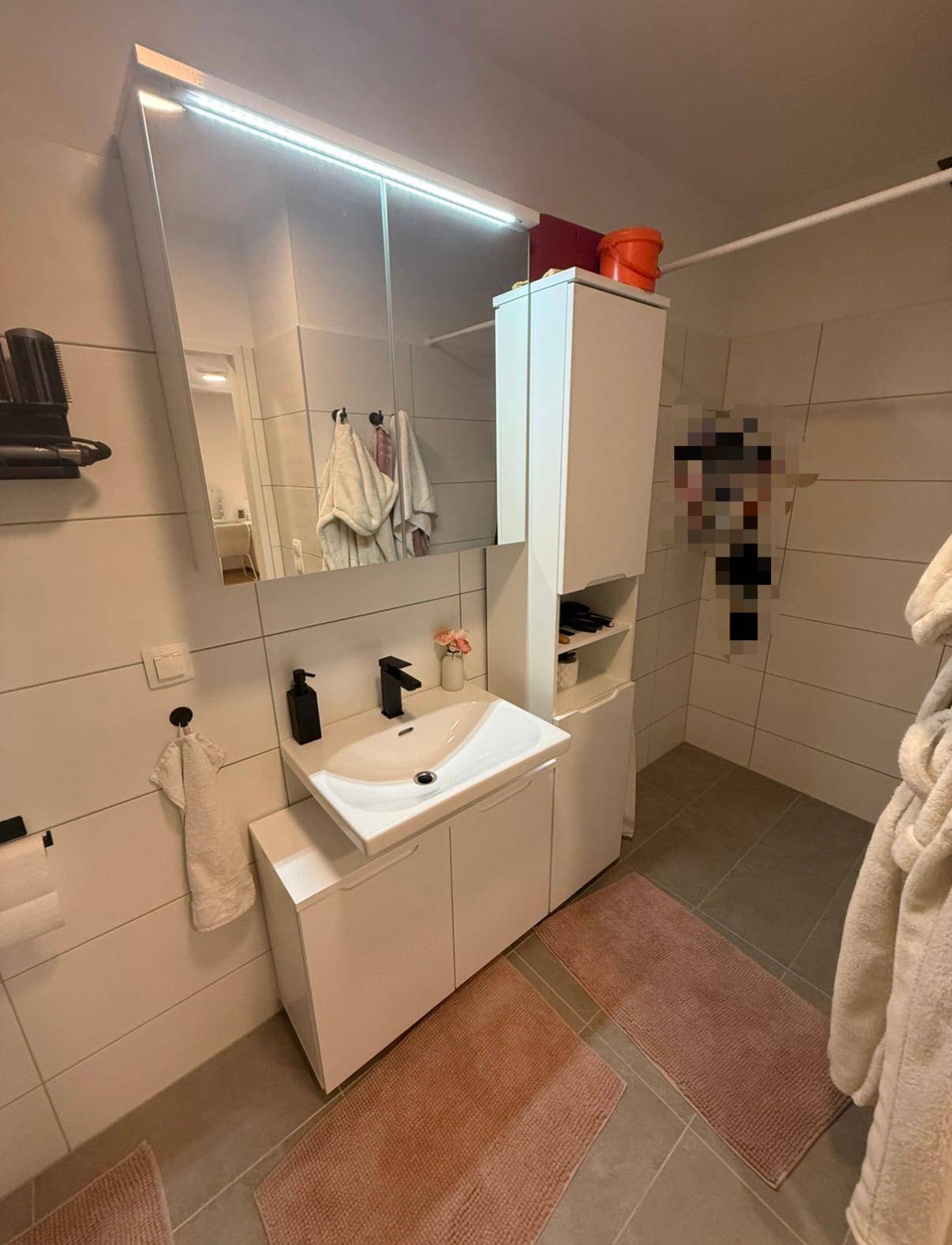 Helles Badezimmer mit modernem Waschbecken, Spiegelschrank und Fliesen.