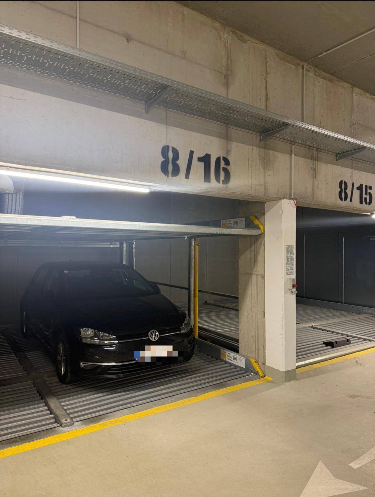 Tiefgarage mit mechanischem Parksystem und einem geparkten Auto.