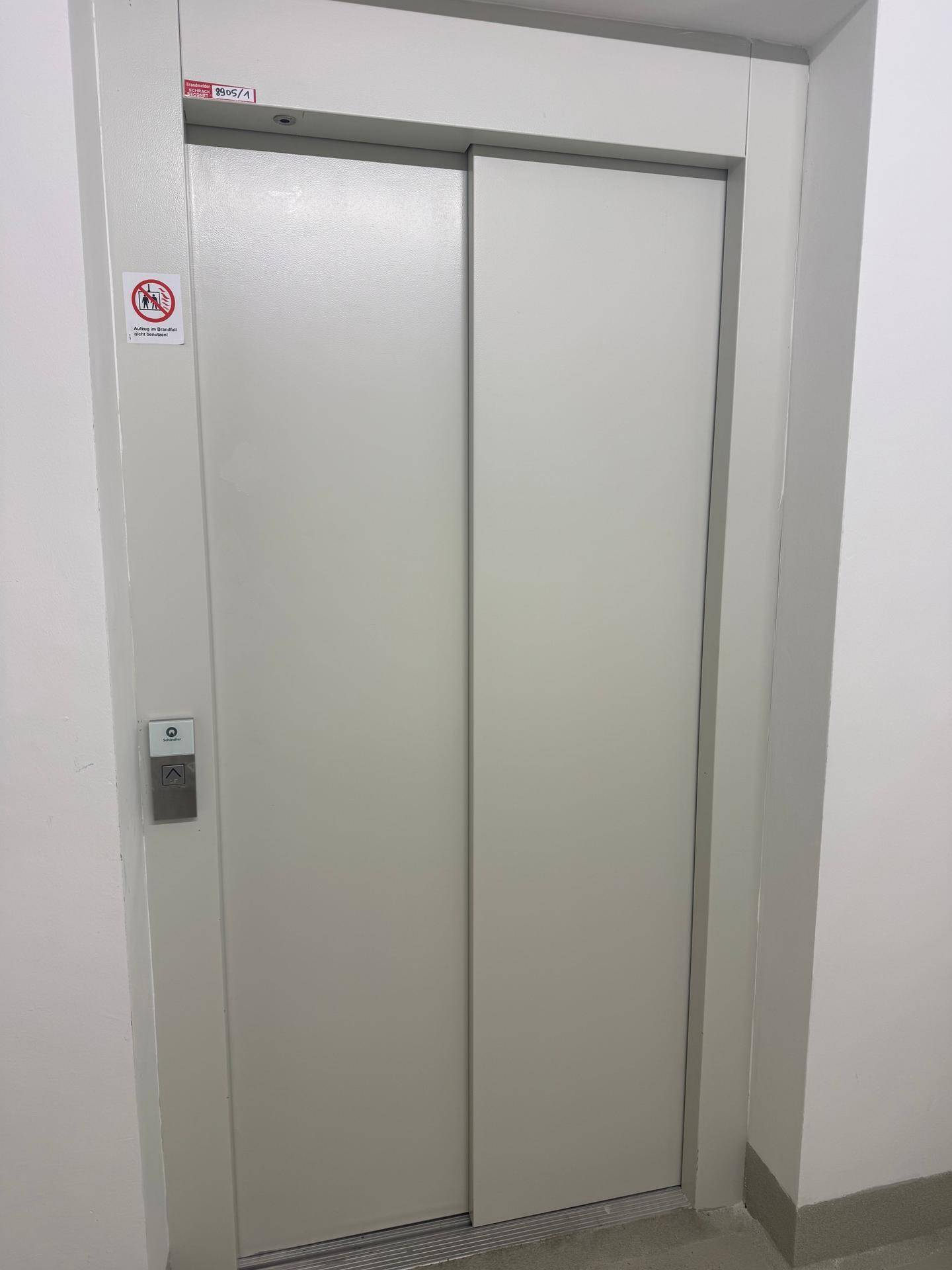 Moderne Aufzugtüren in einem hellen Flur des Wohngebäudes.