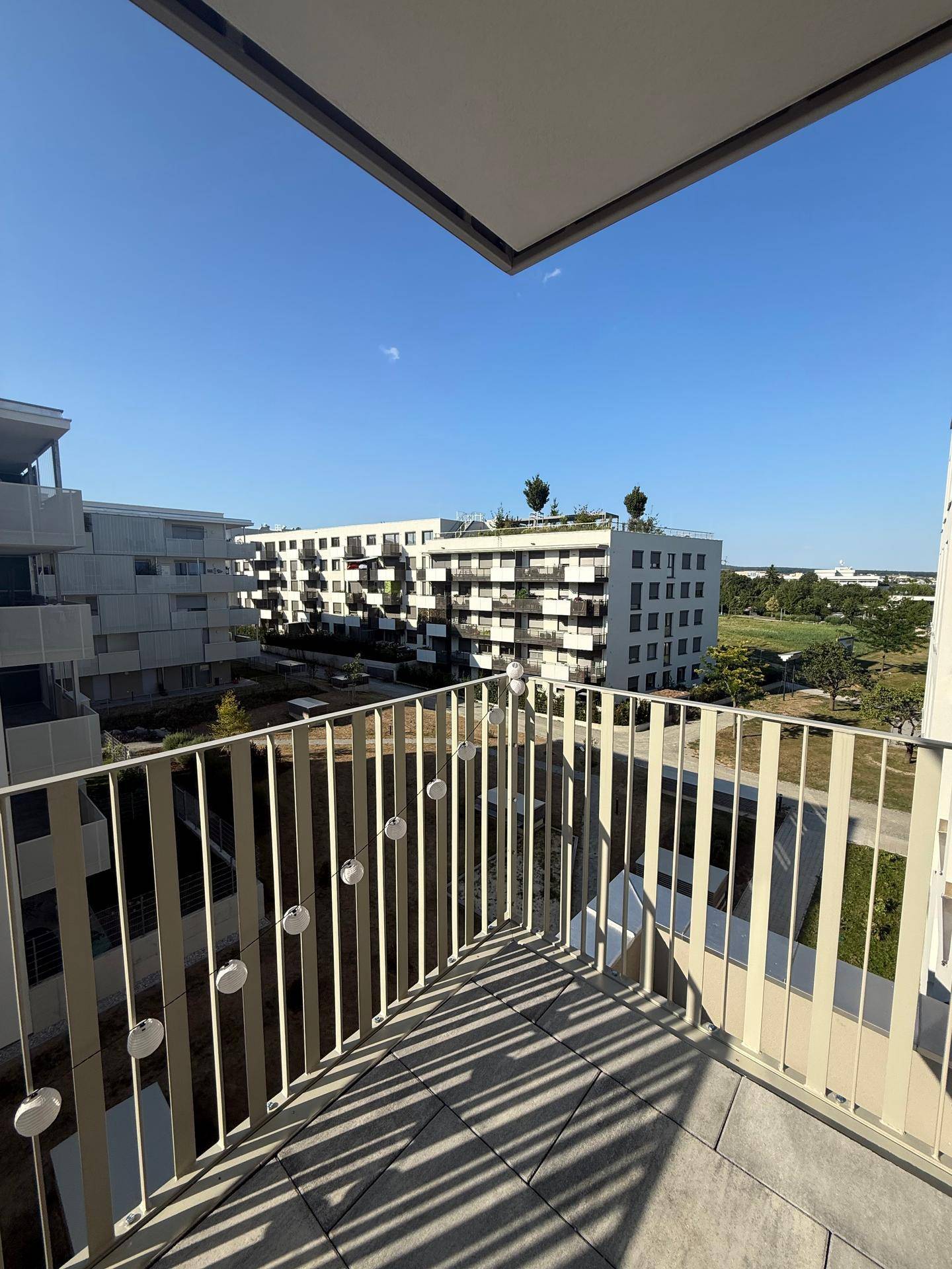 Geräumiger Balkon mit Weitblick auf die umliegenden modernen Gebäude und Grünflächen.