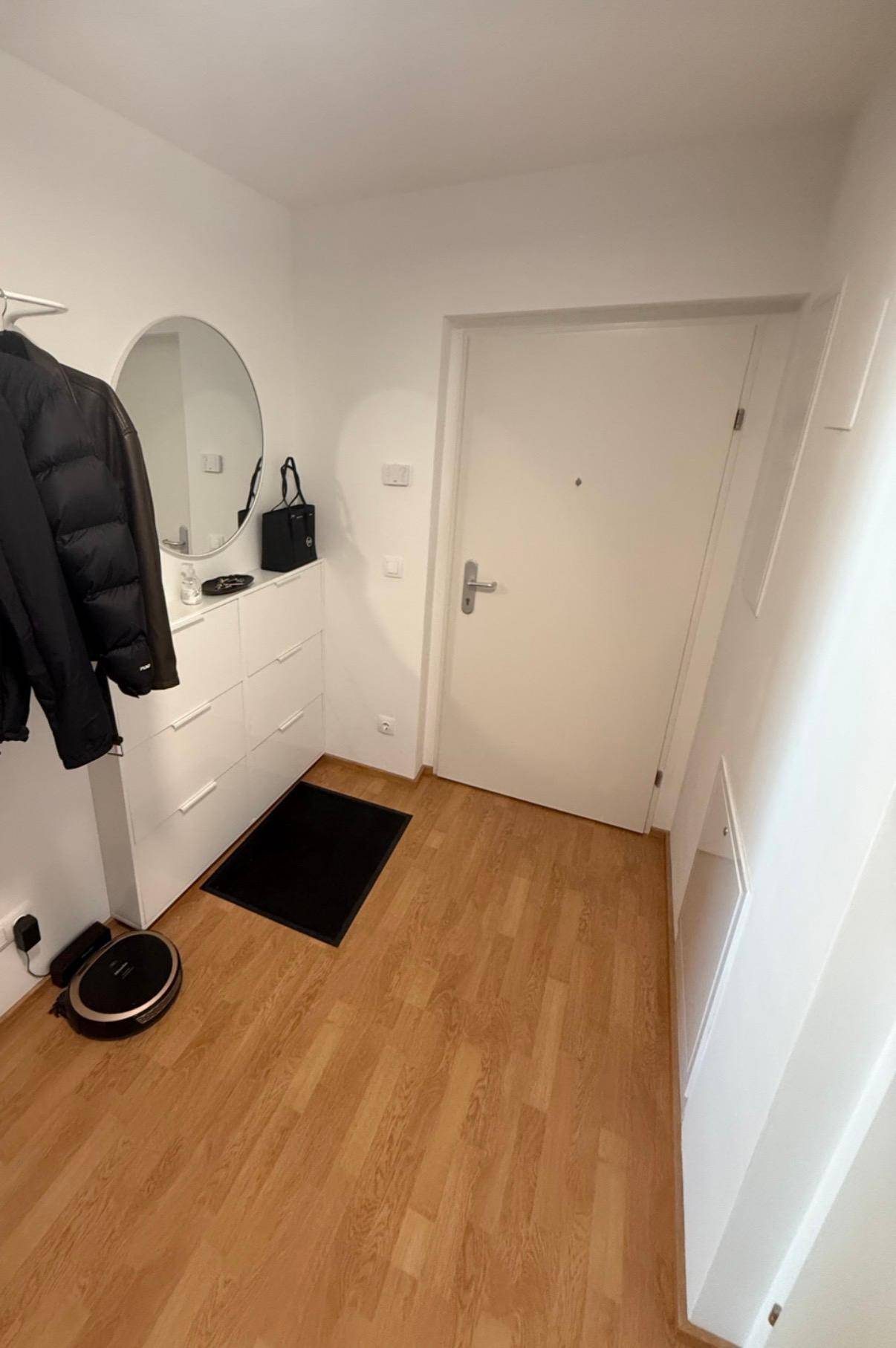 Heller Eingangsbereich der Wohnung mit Laminatboden und Garderobe.