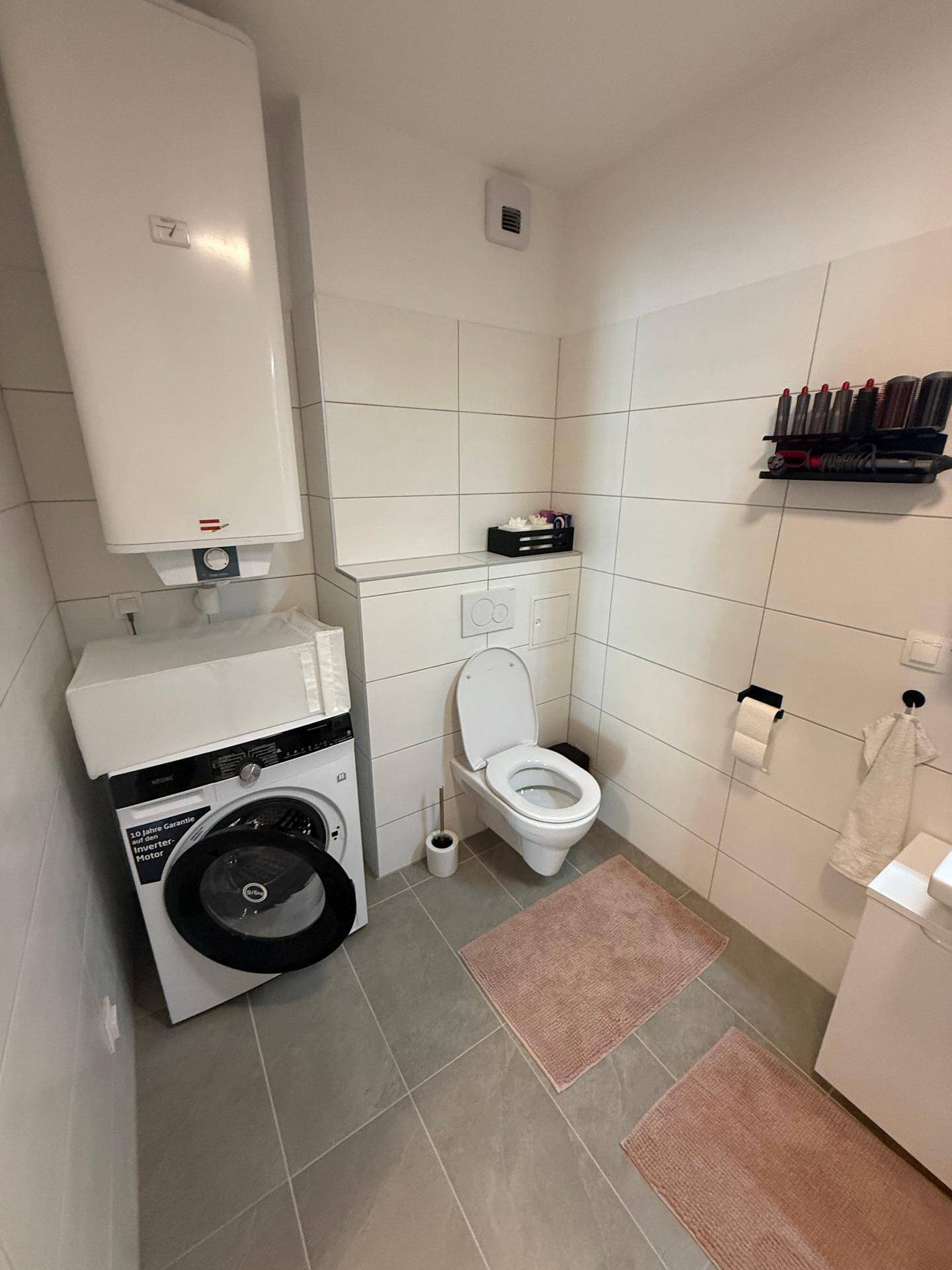 Modernes Badezimmer mit Toilette, Waschmaschine und Warmwasserboiler.