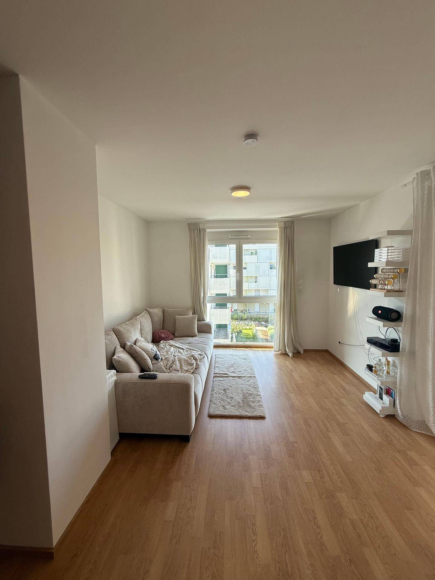 Gemütliches Wohnzimmer mit großem Sofa, Fernseher und Laminatboden.