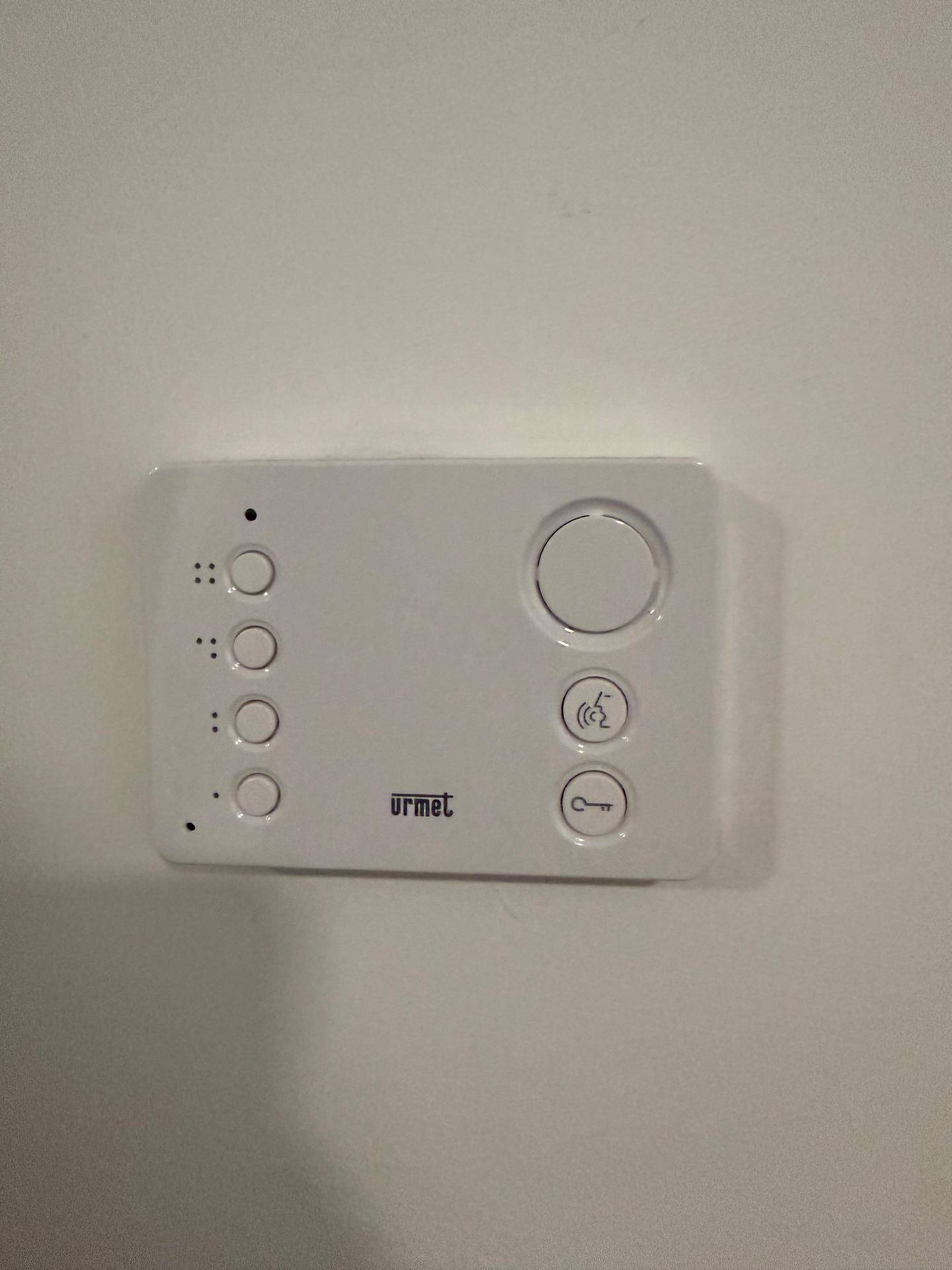 Moderne Gegensprechanlage an einer weißen Wand im Eingangsbereich.