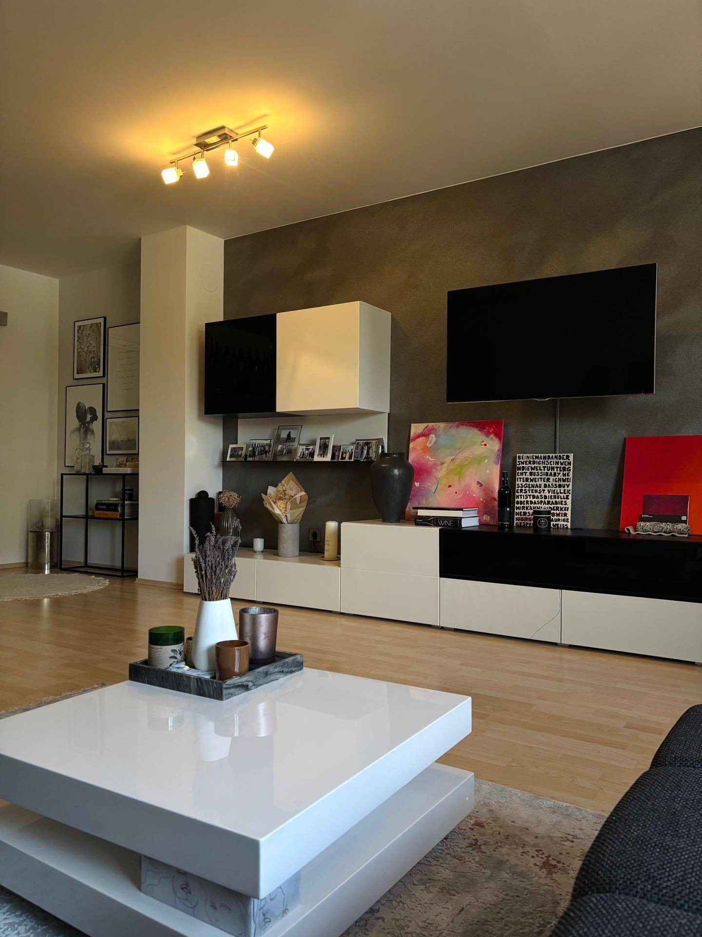 Gemütliches Wohnzimmer mit modernem TV-Möbel, stilvoller Dekoration und dunkler Akzentwand.