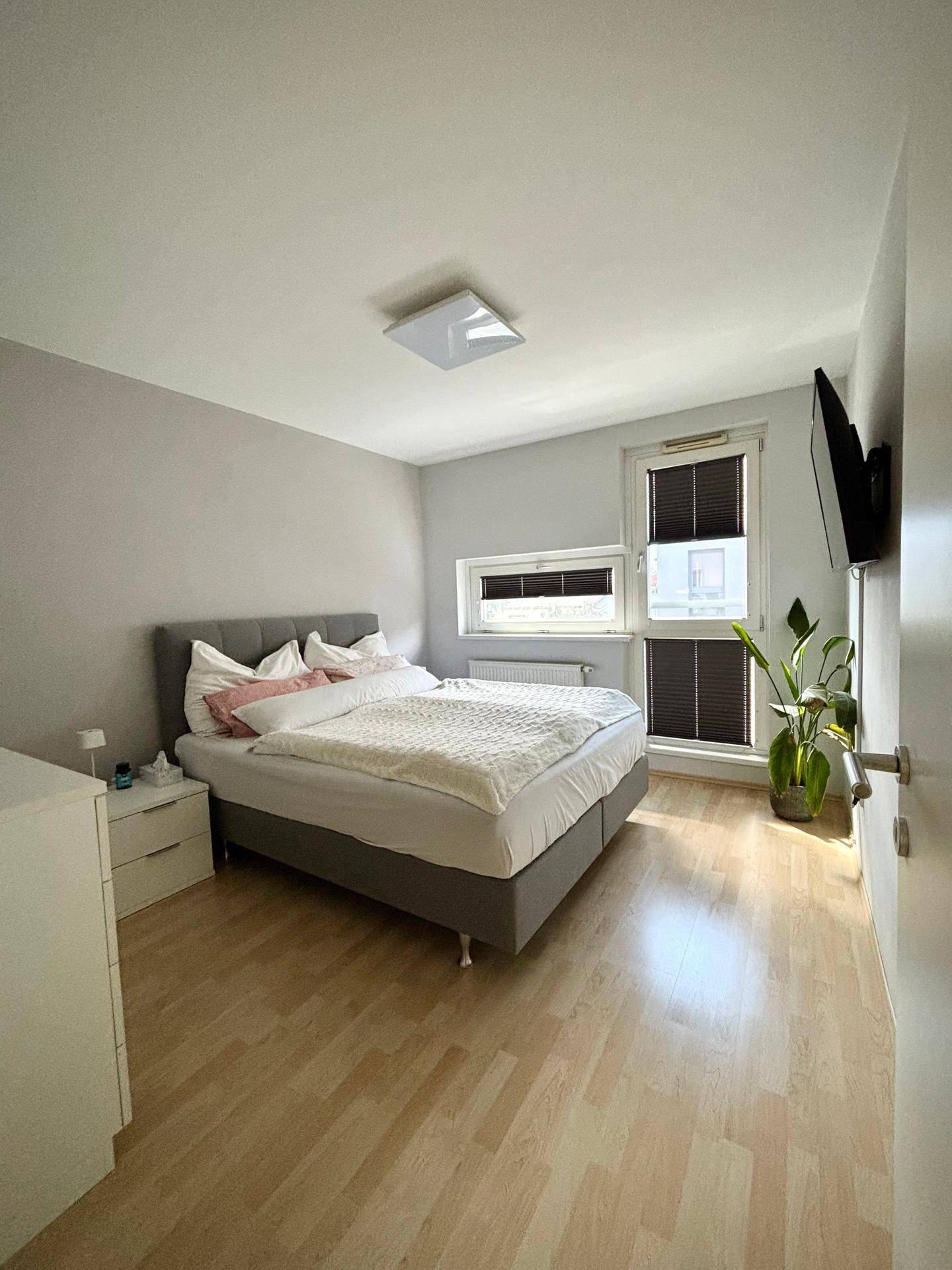 Helles Schlafzimmer mit bequemem Doppelbett, schlichten Möbeln und natürlichem Lichteinfall.