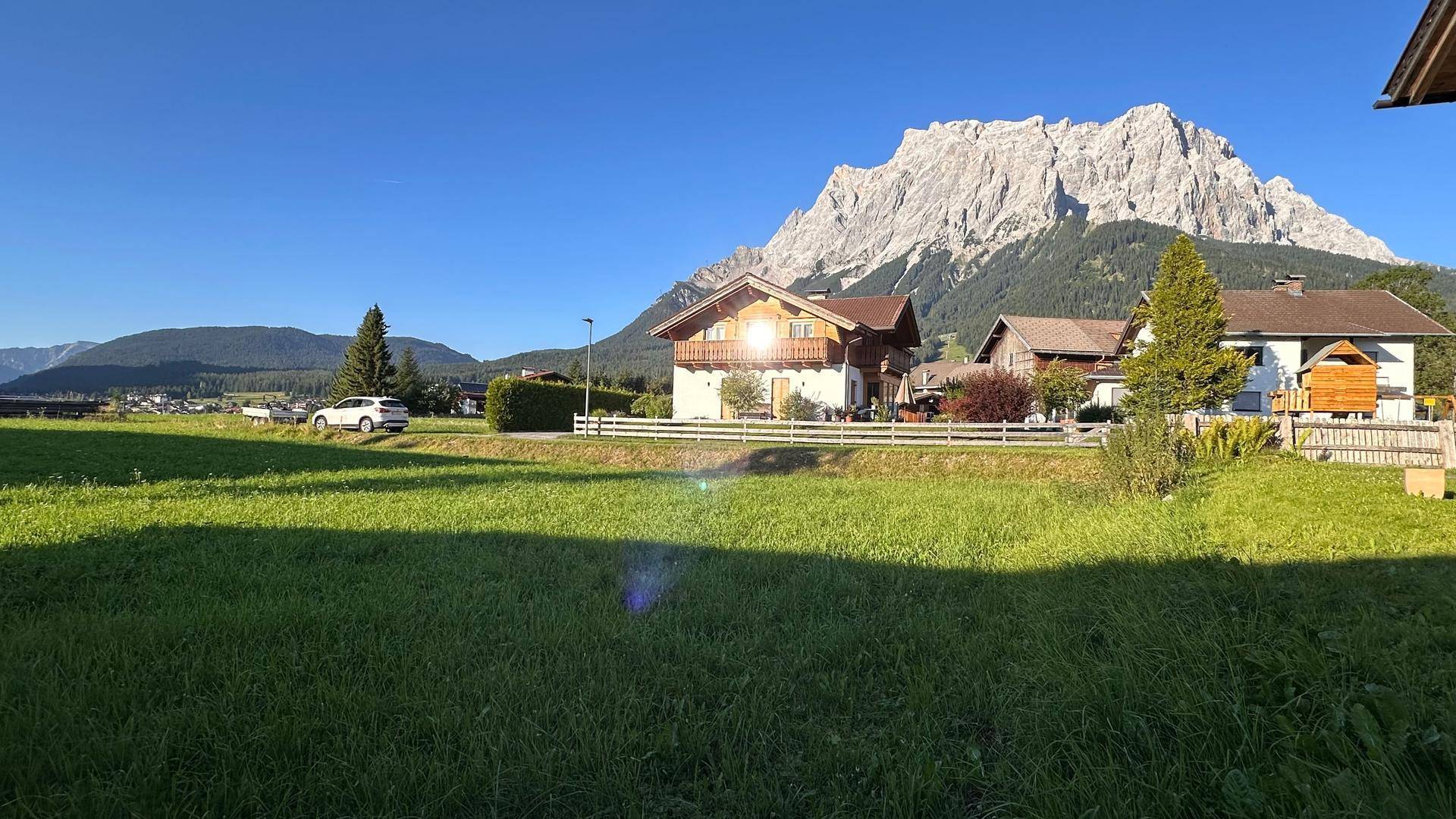 Alpines Haus mit Holzbalkonen und einem atemberaubenden Bergblick unter strahlend blauem Himmel.