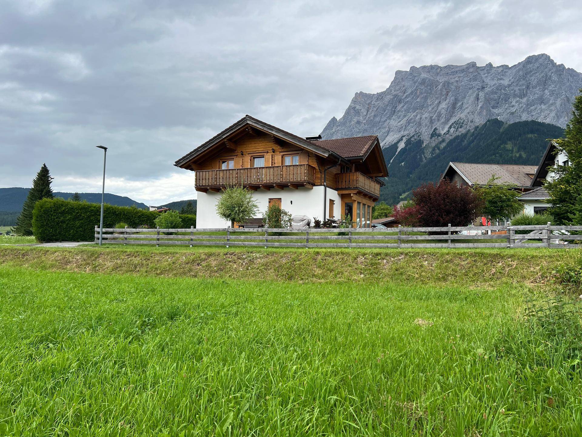 Alpines Wohnhaus mit zwei Holzbalkonen und einem weiten Blick auf die beeindruckende Bergwelt.