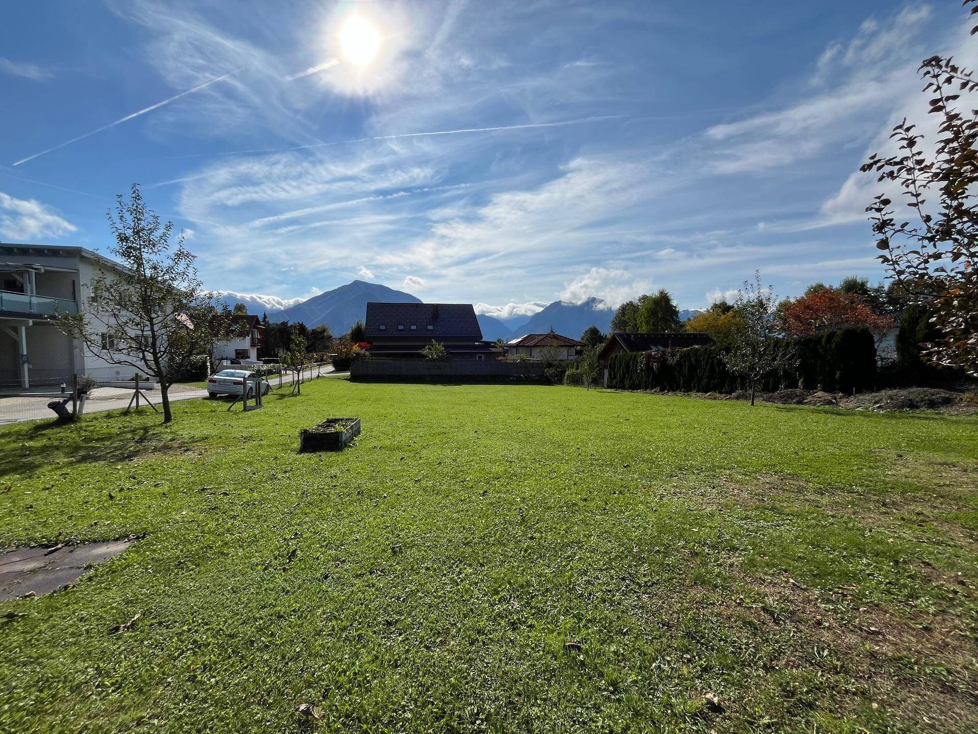 Sonnenverwöhnter Gartenbereich mit weitläufiger Rasenfläche und Panoramablick auf die umliegenden Berge.