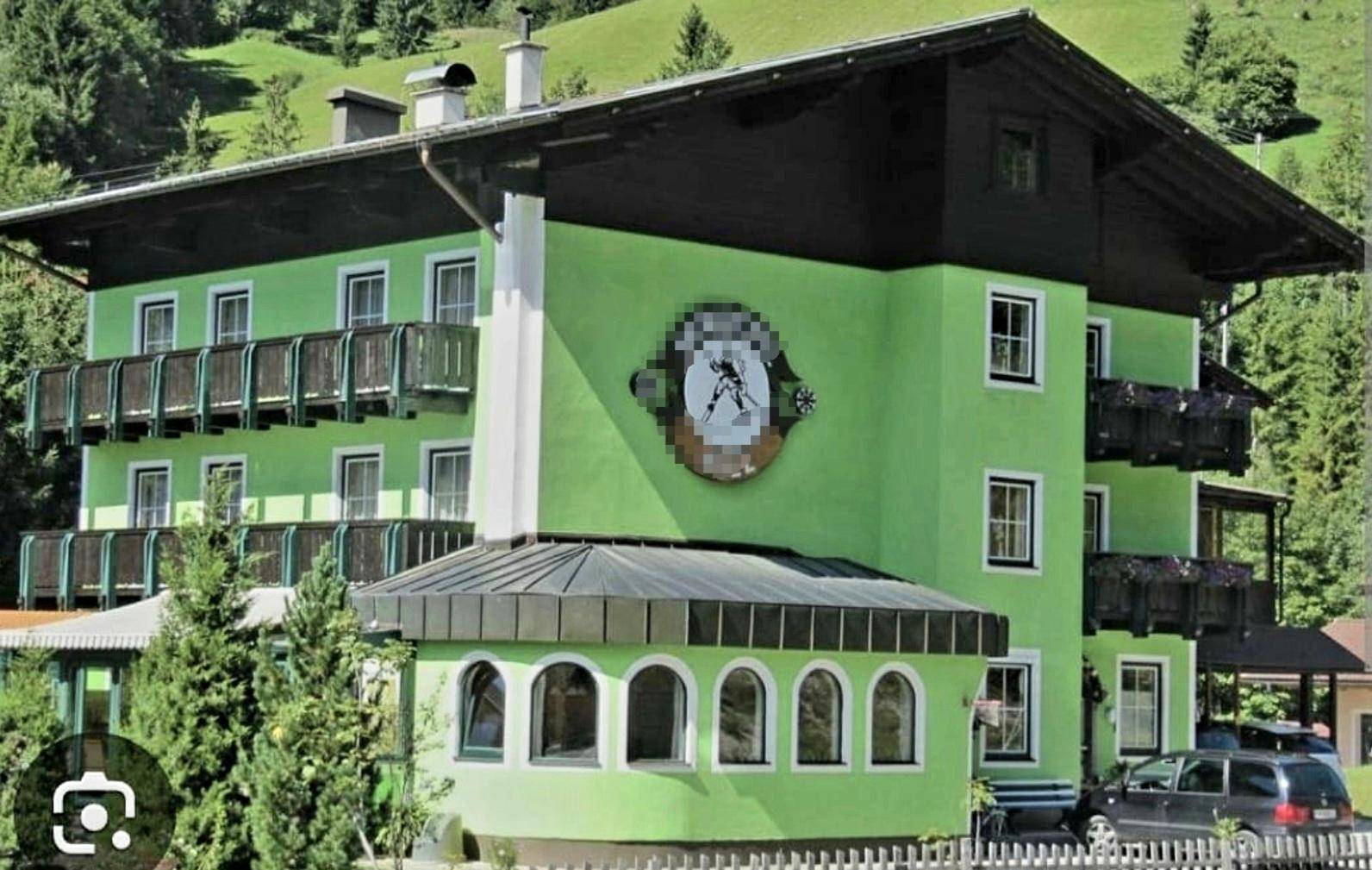 Traditionelles Gebäude im alpinen Stil mit grüner Fassade und Holzbalkonen.