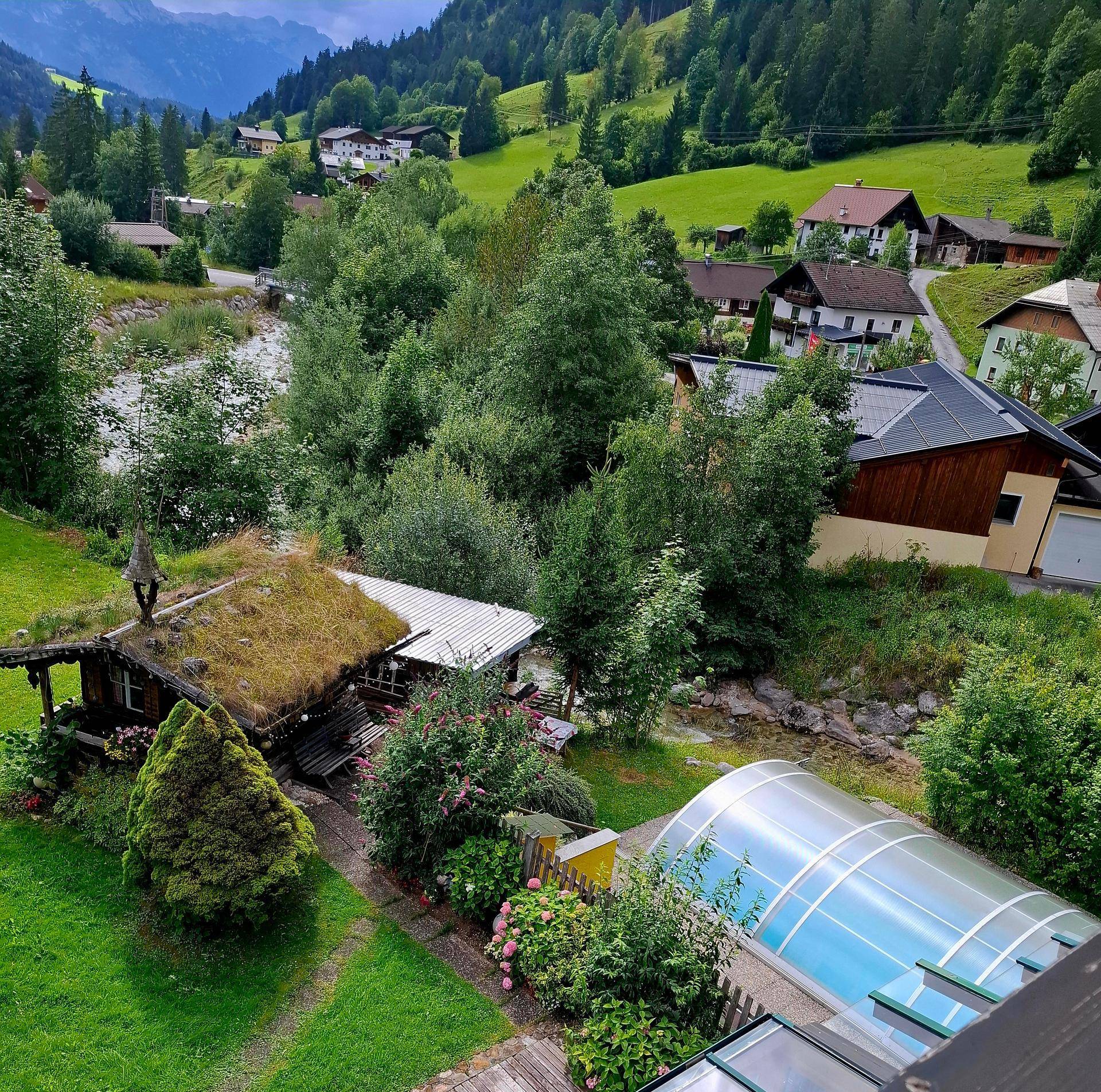 Panoramablick auf das Anwesen mit Pool, begrüntem Dach und umliegender alpiner Landschaft.