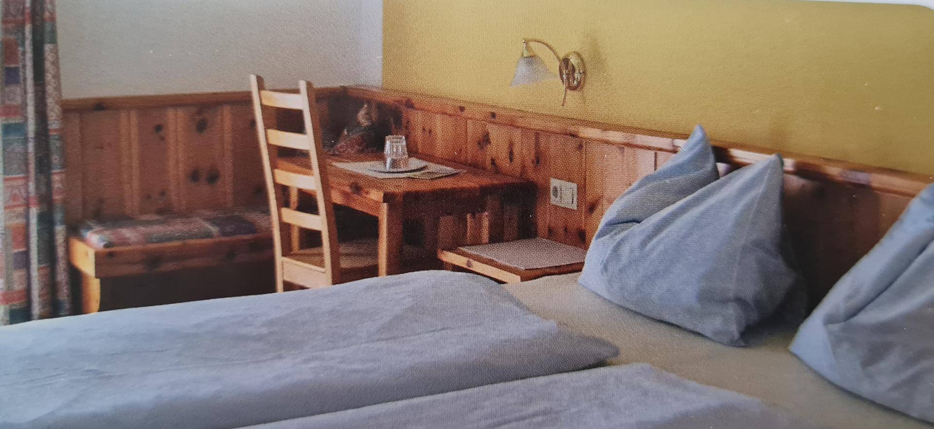 Gemütliches Schlafzimmer im alpinen Stil mit Holzvertäfelung, integrierter Sitzbank und Doppelbett.