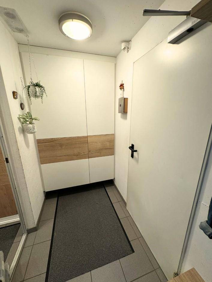 Heller Eingangsbereich mit modernen Einbauschränken in Weiß und Holzoptik.