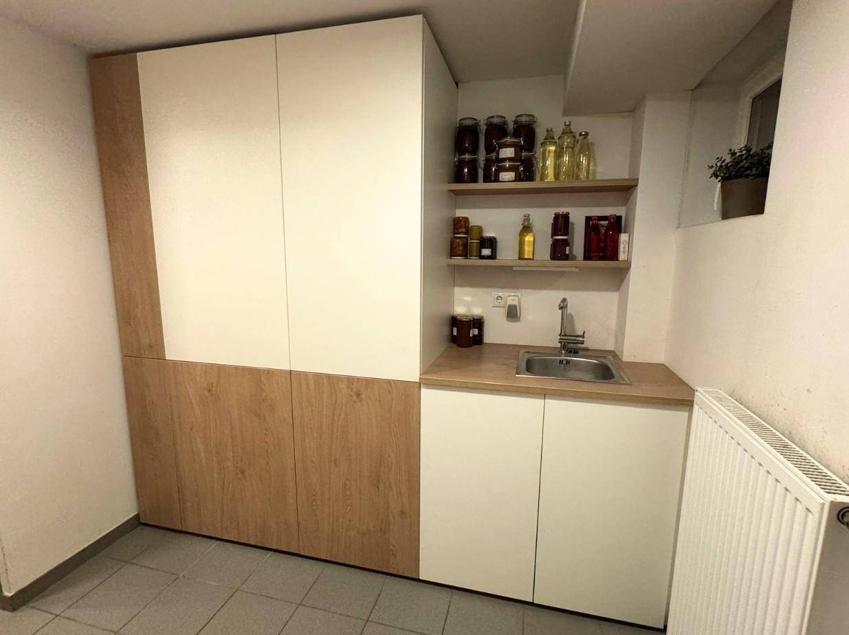 Praktischer Hauswirtschaftsraum mit Spülbecken, Regalen und Heizkörper im Kellerbereich.
