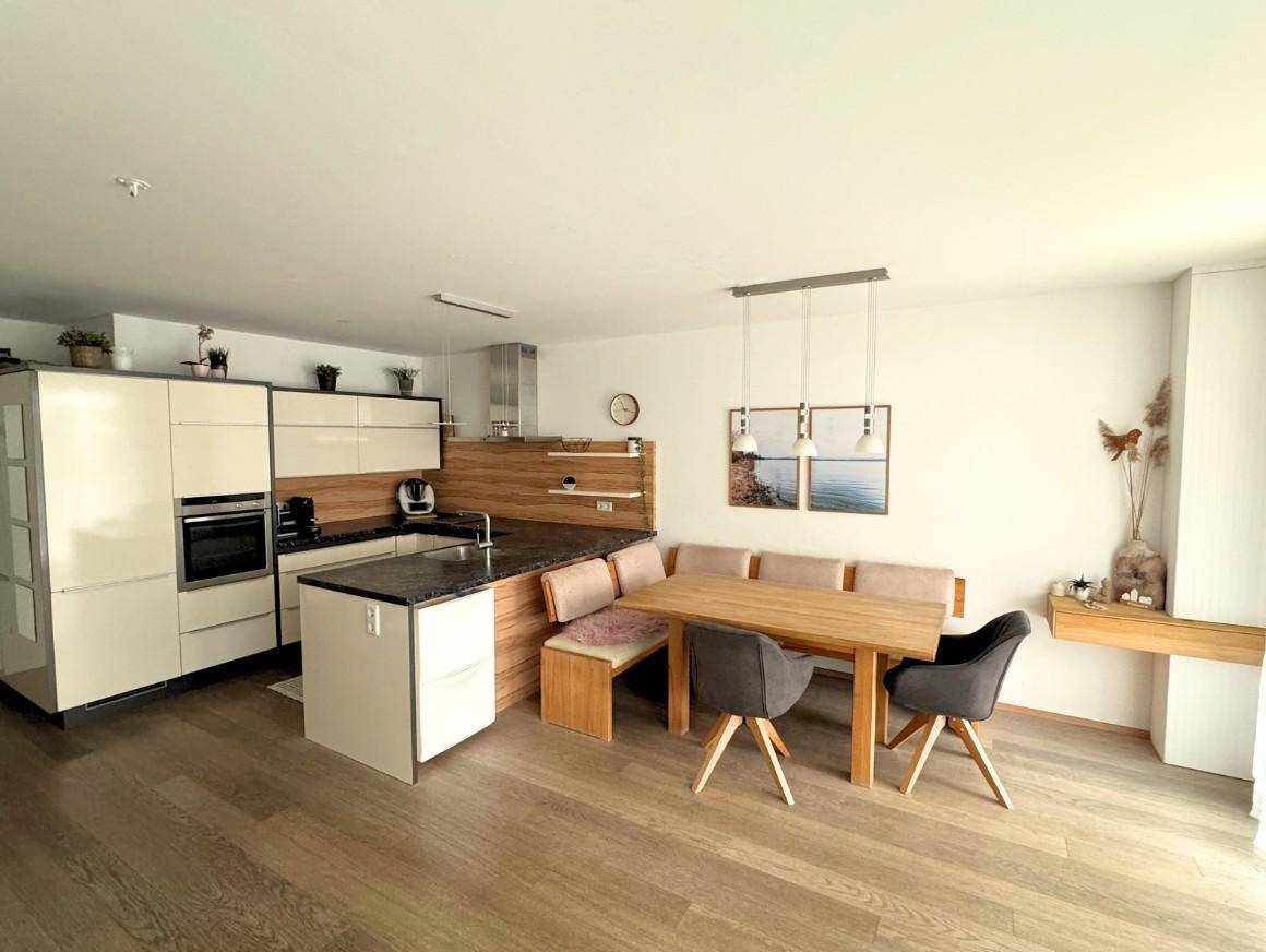 Moderne Einbauküche mit Essbereich, integrierter Sitzbank und hellem Laminatboden.