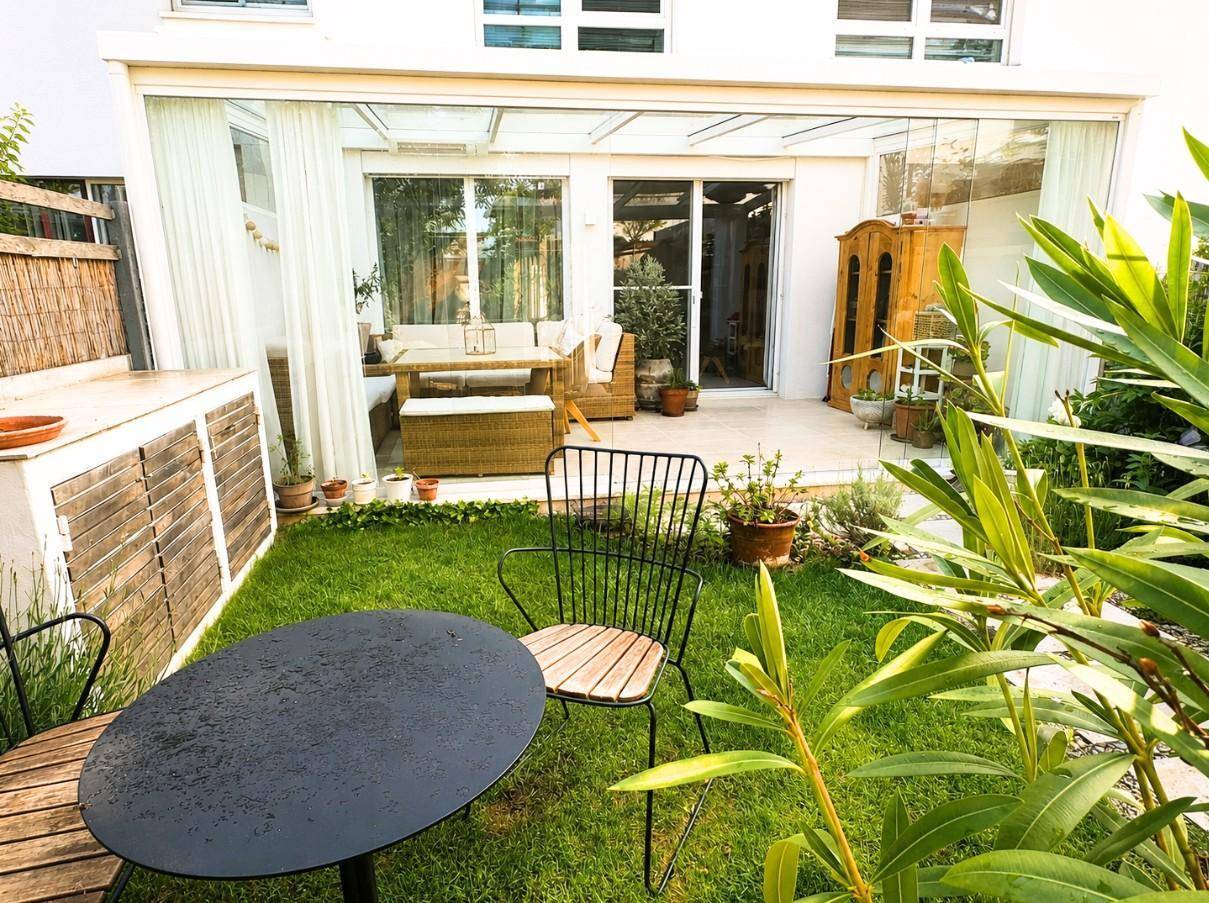 Gepflegter Gartenbereich mit Rasenfläche und einer überdachten Terrasse mit Sitzgelegenheiten.