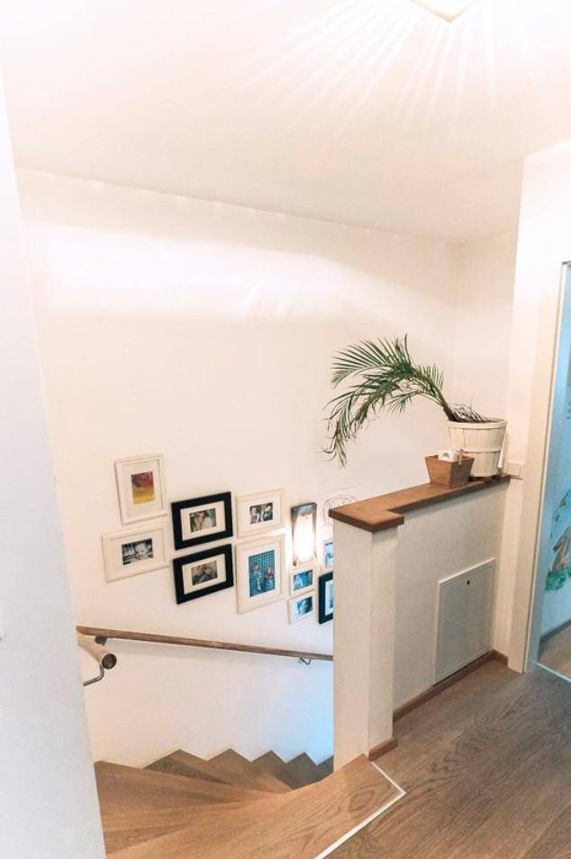 Heller Treppenaufgang mit Holzstufen und einer dekorativen Bildergalerie an der Wand.