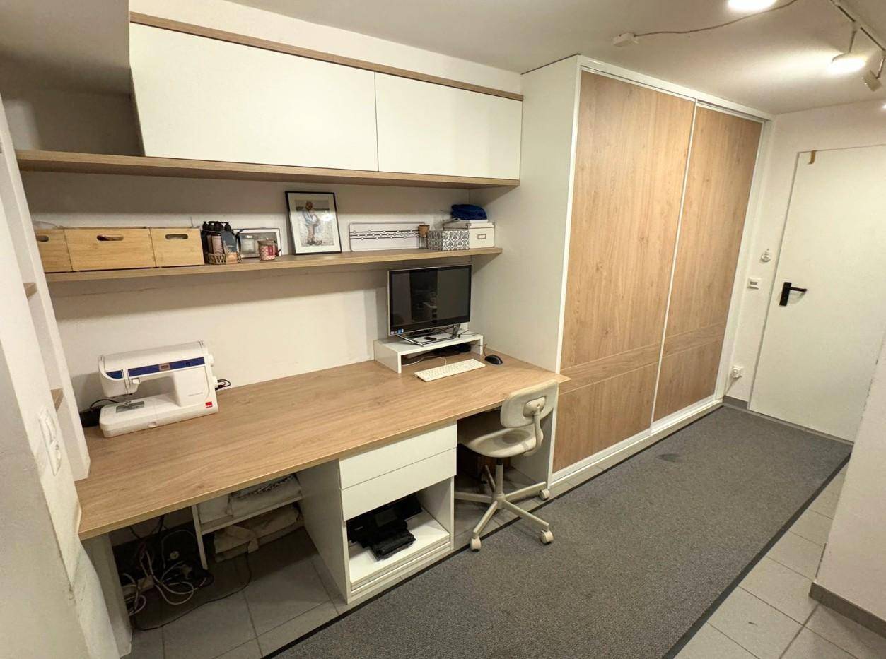 Funktionaler Arbeitsbereich mit langem Schreibtisch, Regalen und integriertem Kleiderschrank.