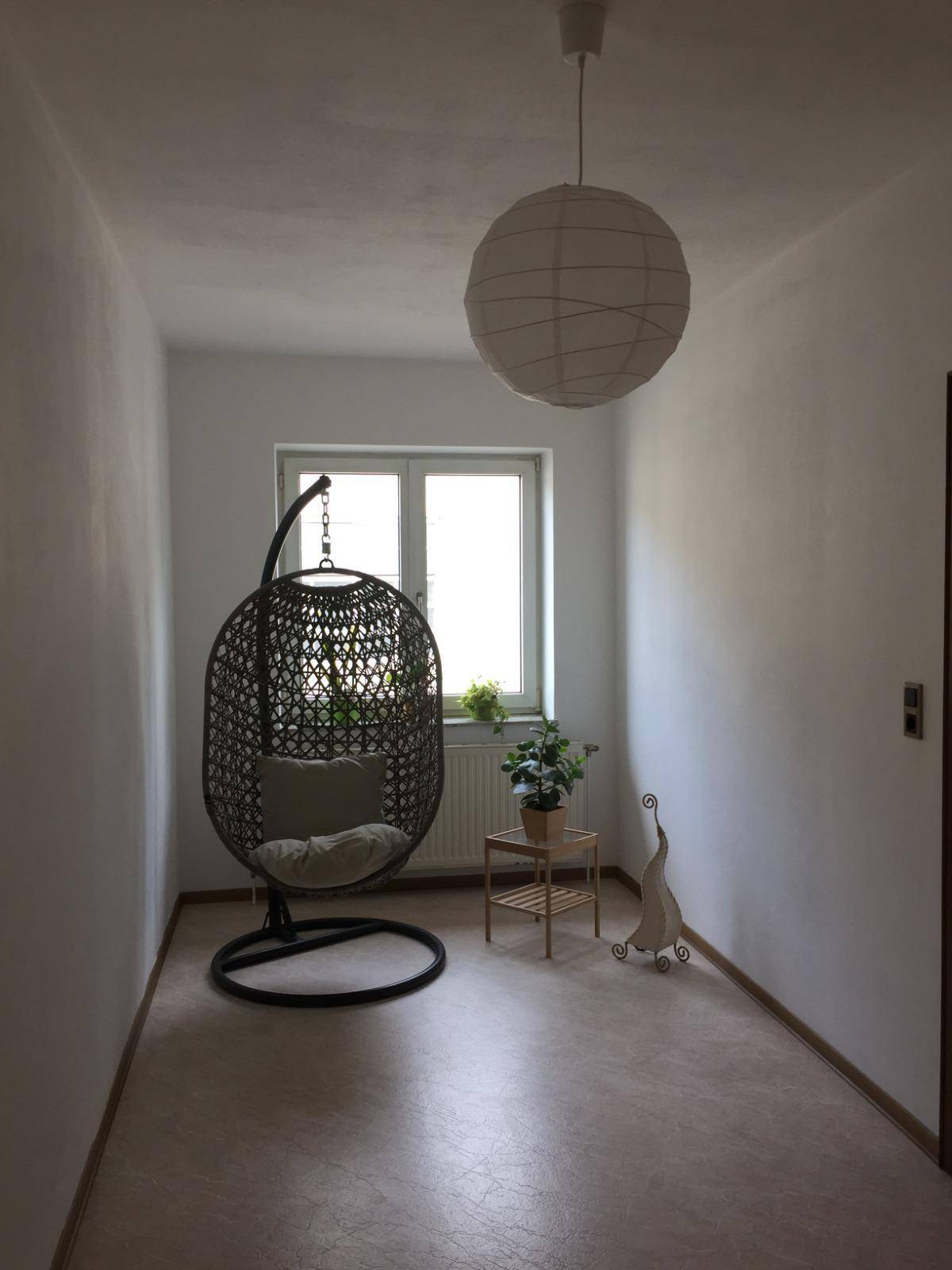 Heller Flur mit Hängesessel, Fenster, Pflanzen und modernem Dekor.