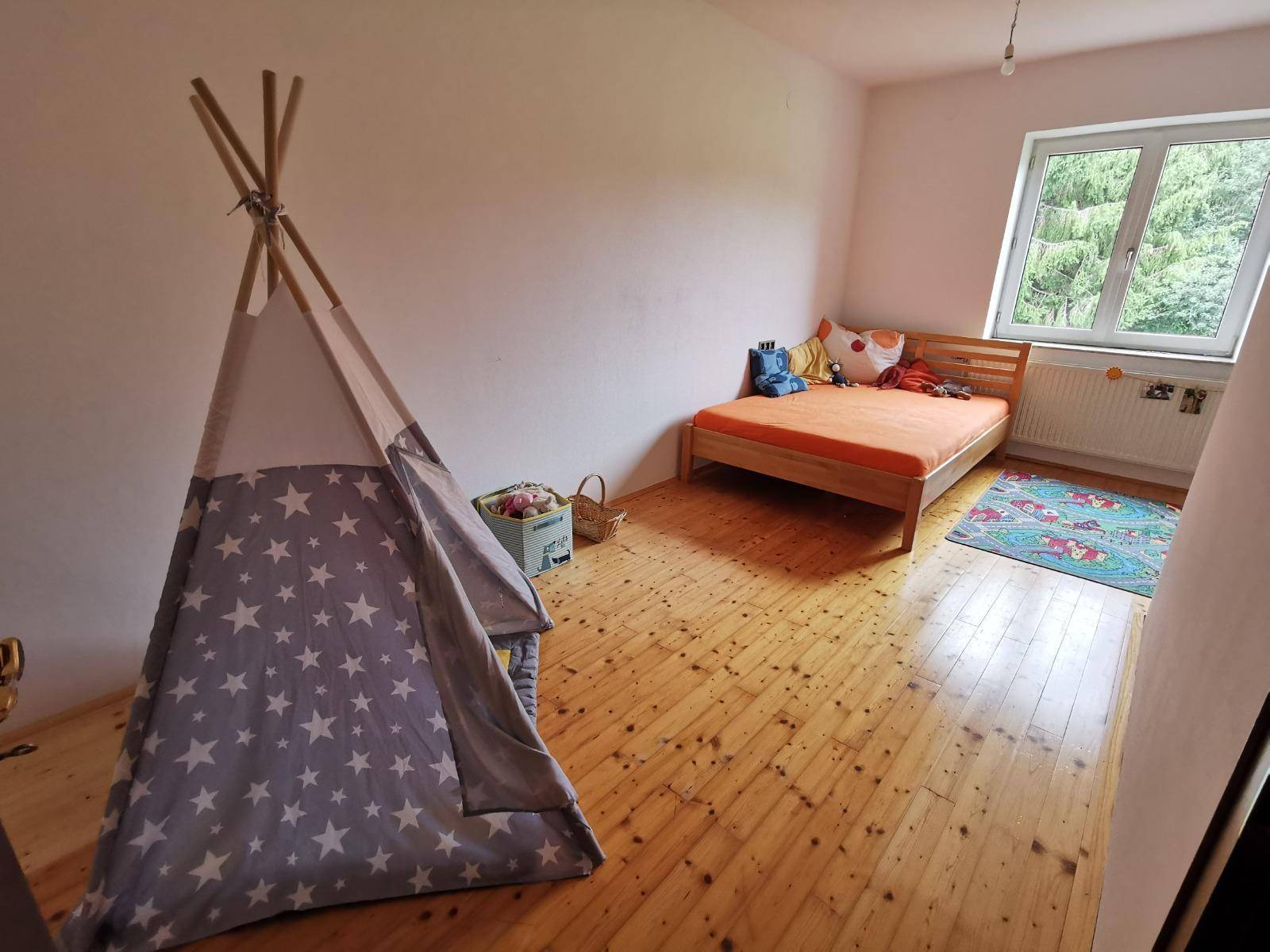 Kinderzimmer mit Holzboden, Einzelbett, Spielzelt und Blick ins Grüne.