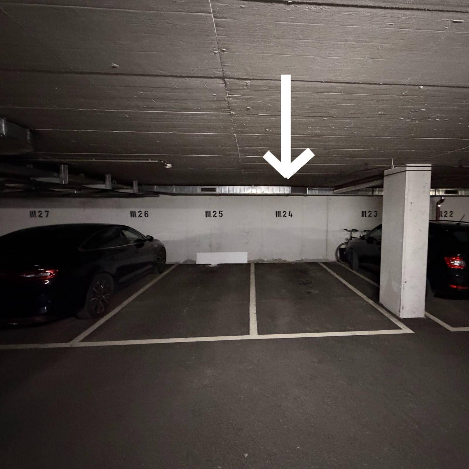 Leere Parkplätze in der Tiefgarage mit klaren Markierungen und einem Richtungspfeil am Boden.