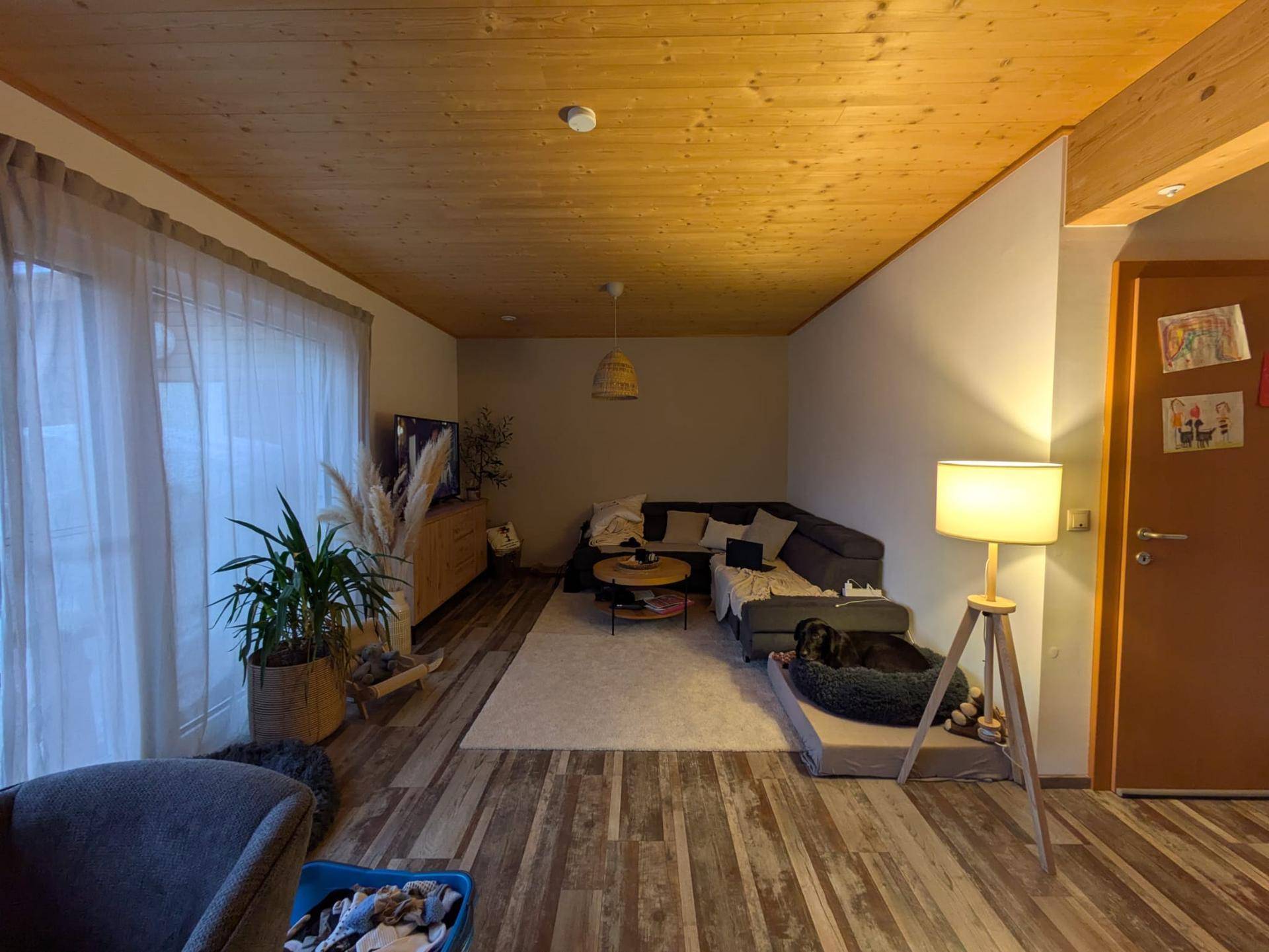 Geräumiges Wohnzimmer mit L-förmigem Sofa, Holzboden und indirekter Beleuchtung.
