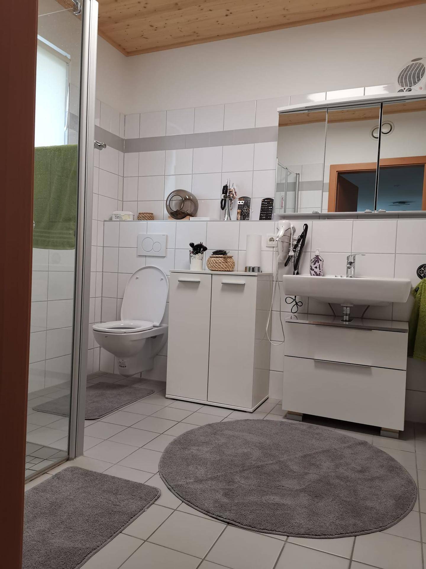 Modernes Badezimmer mit Dusche, WC, Waschbecken und Spiegelschrank.