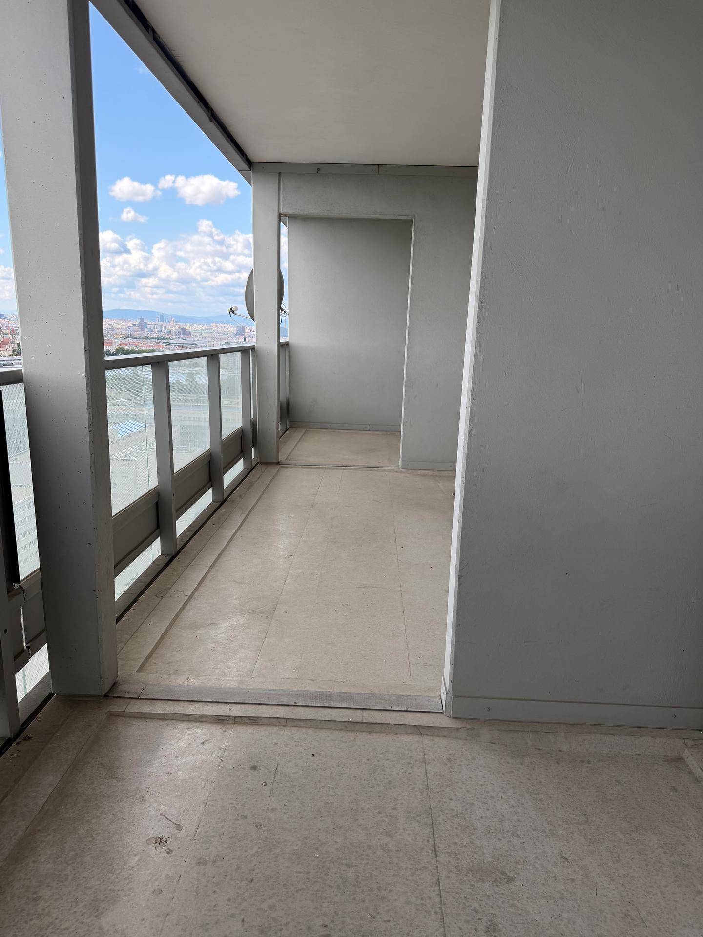 Heller Balkon mit Fliesenboden und Panoramablick auf die umliegende Stadtlandschaft und Gebäude.
